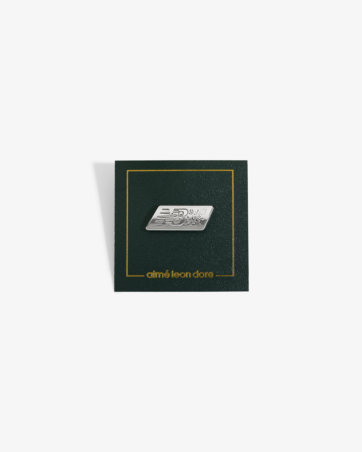 ALD / New Balance Logo Pin: Silver pin with NB, on green card with gold aimé leon dore text at the bottom.