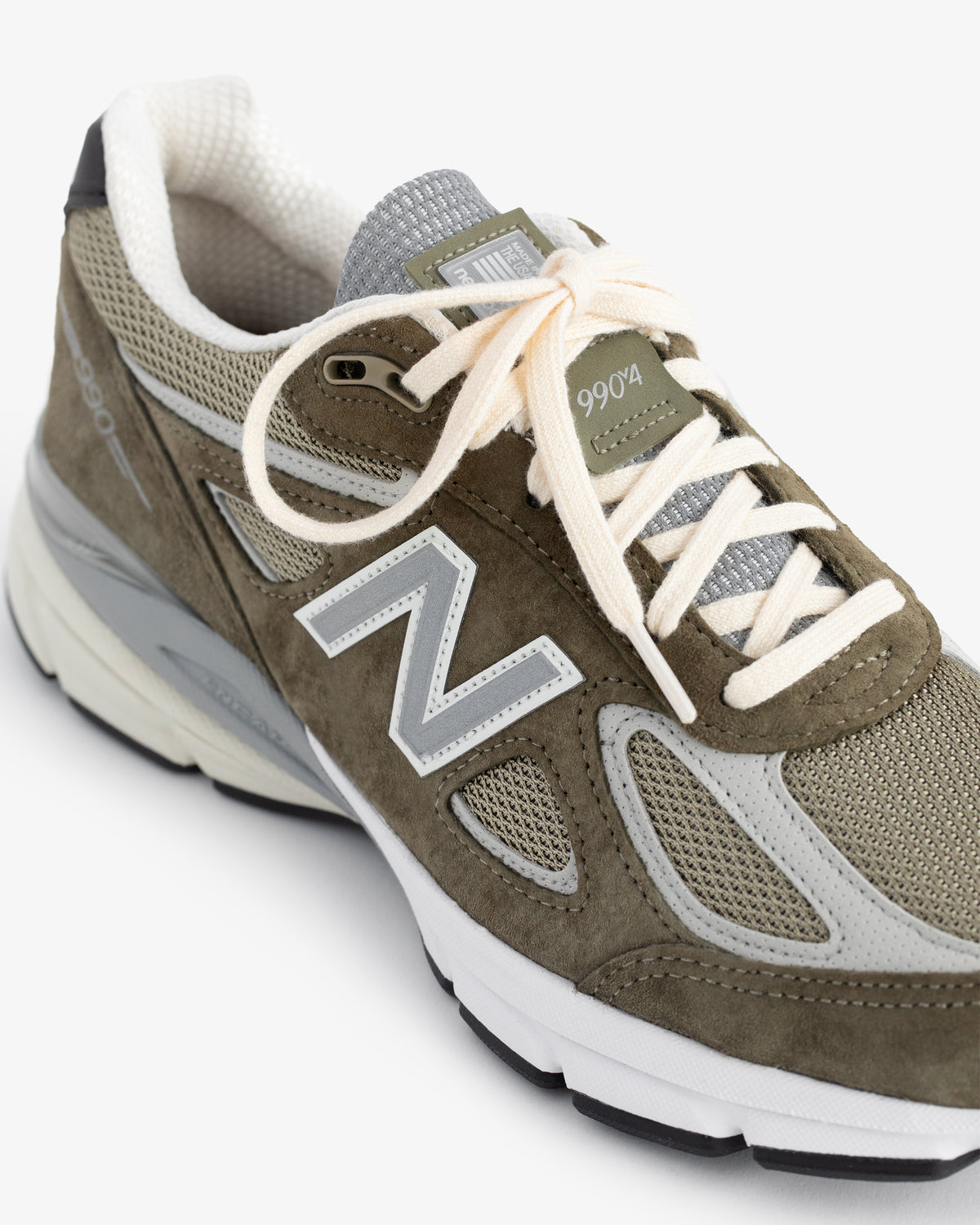 Olive green ALD / New Balance 990v4 with white laces and gray mesh accents, shown from an angle.