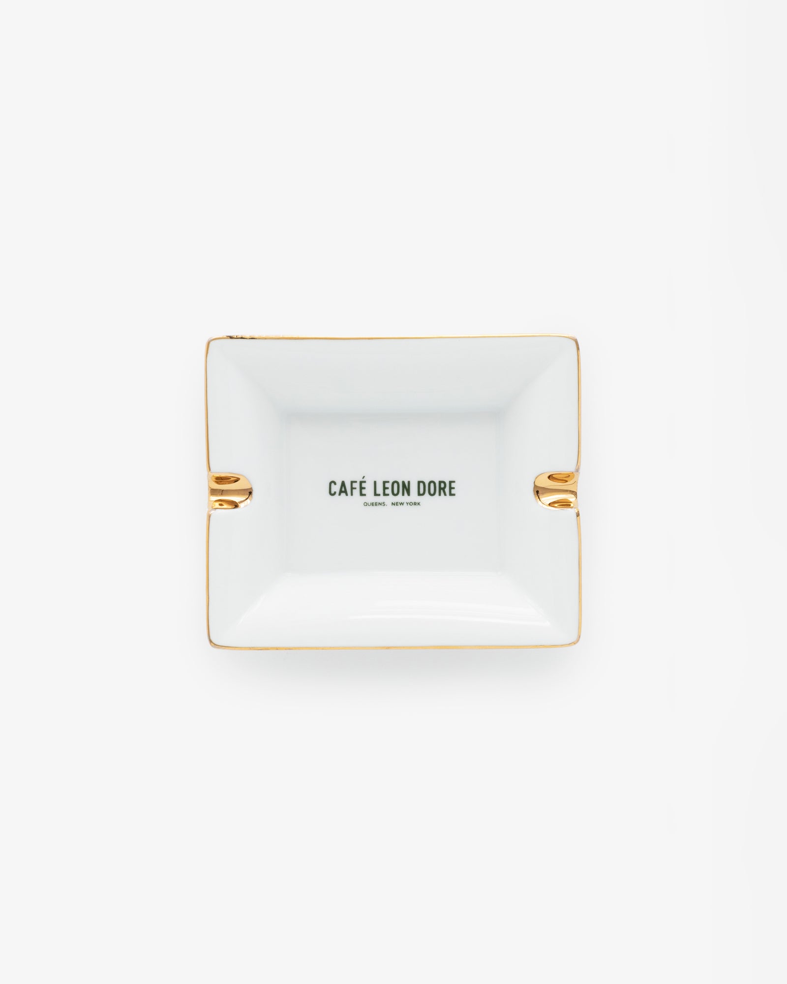 Café Leon Dore Ashtray—rectangular white with gold accents and CAFÉ LEON DORE text centered, on a plain background.