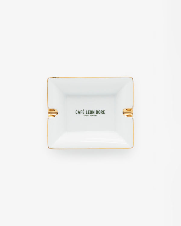 Café Leon Dore Ashtray—rectangular white with gold accents and CAFÉ LEON DORE text centered, on a plain background.