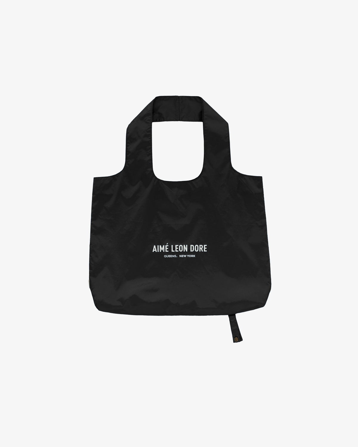 Packable Logo Tote: black reusable bag with AIMÉ LEON DORE and QUEENS, NEW YORK printed in white on front.