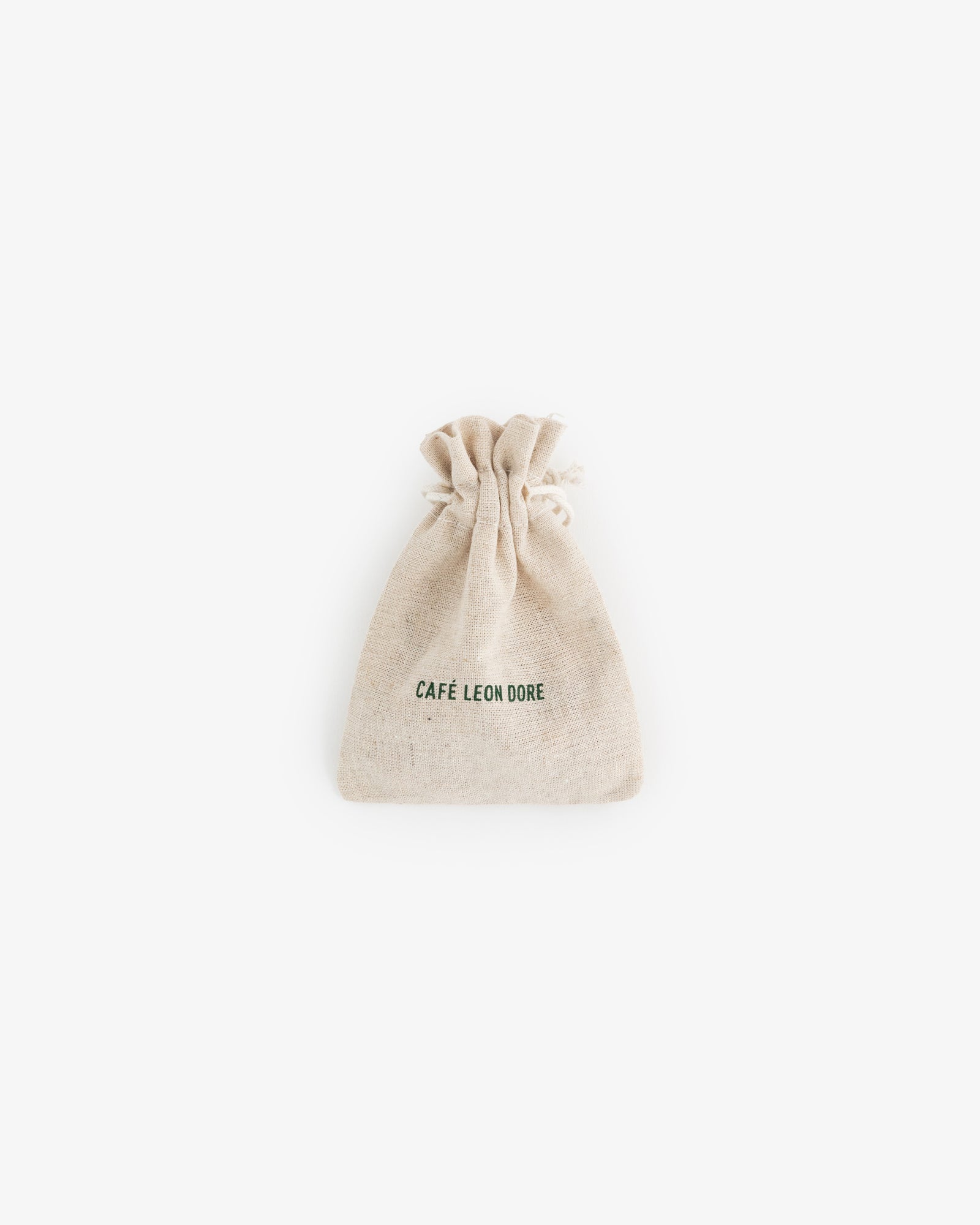 A small beige drawstring pouch for Café Leon Dore Komboloi, with branding on the front, centered on a white background.
