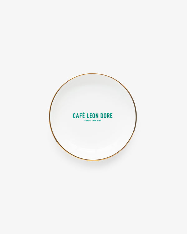 Café Leon Dore Ring Dish: white plate with gold rim, green “CAFÉ LEON DORE, QUEENS, NEW YORK” in center.