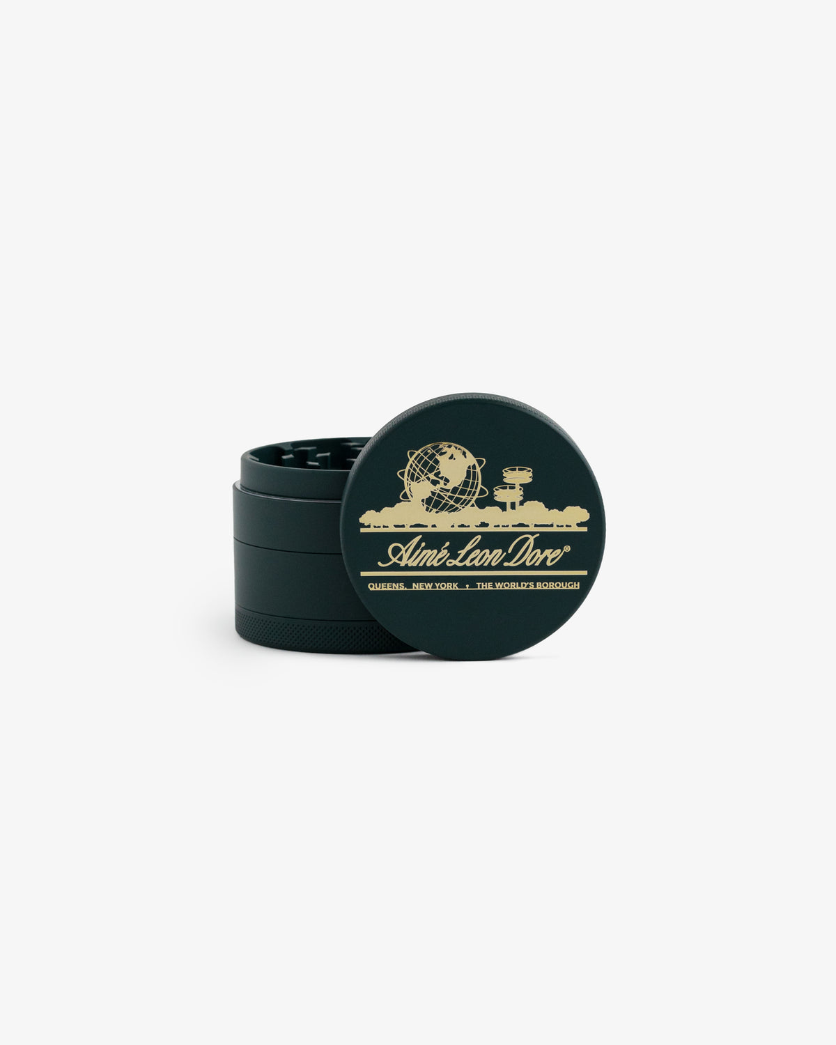 Large Unisphere Herb Grinder in black and gold with globe design and "Aimé Leon Dore, Queens, New York" text on lid.