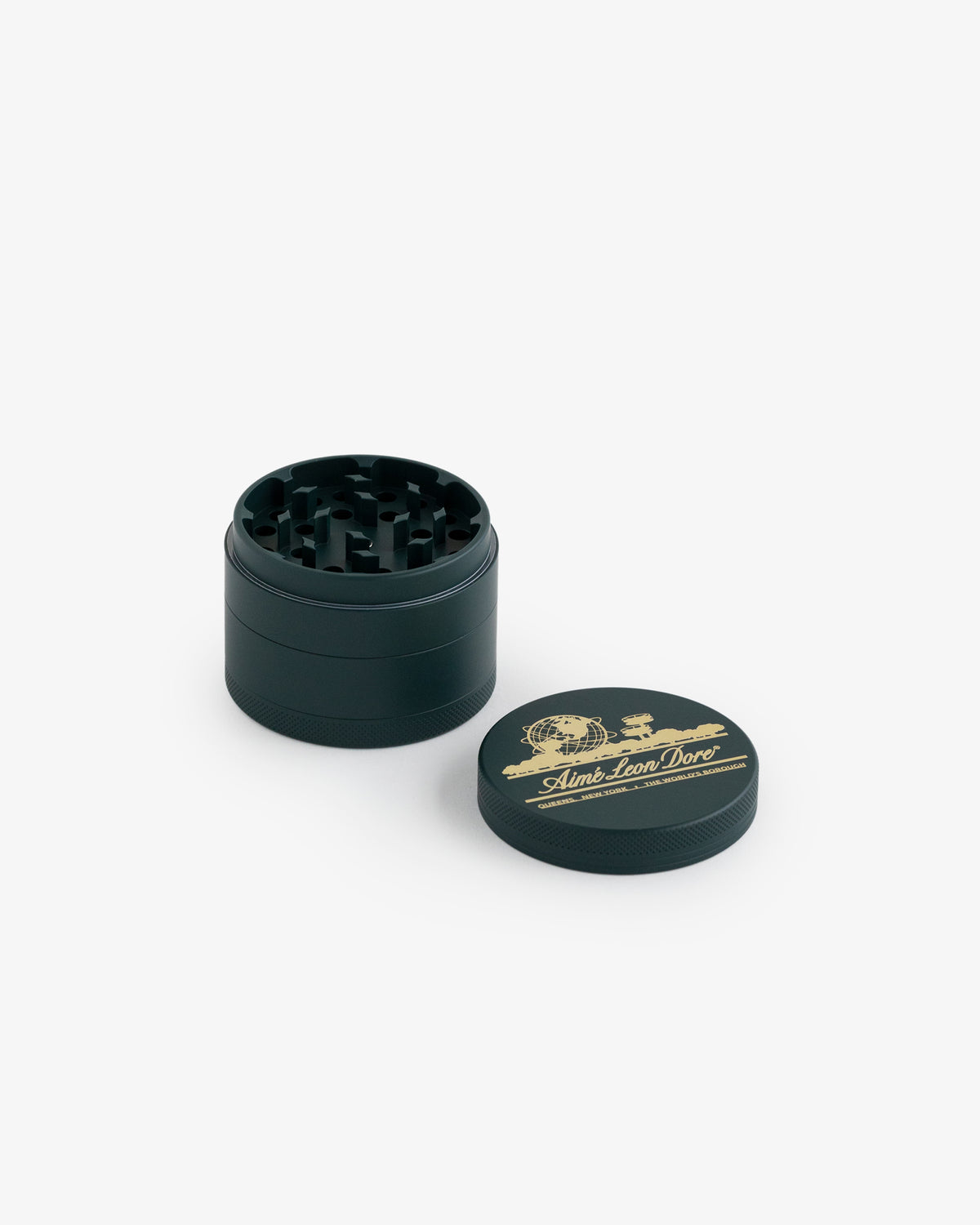 Large Unisphere Herb Grinder shown with lid off, displaying teeth inside; lid features gold logo and Aimé Leon Dore text.