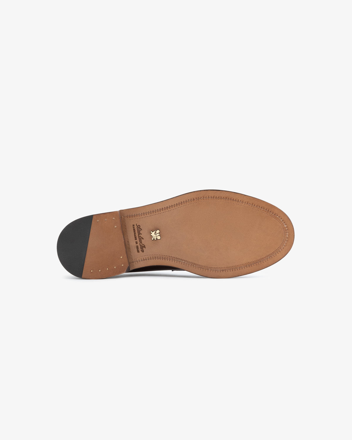 The underside of the Queens Crest Loafer, a brown leather shoe with a black heel and gold emblem near the arch.