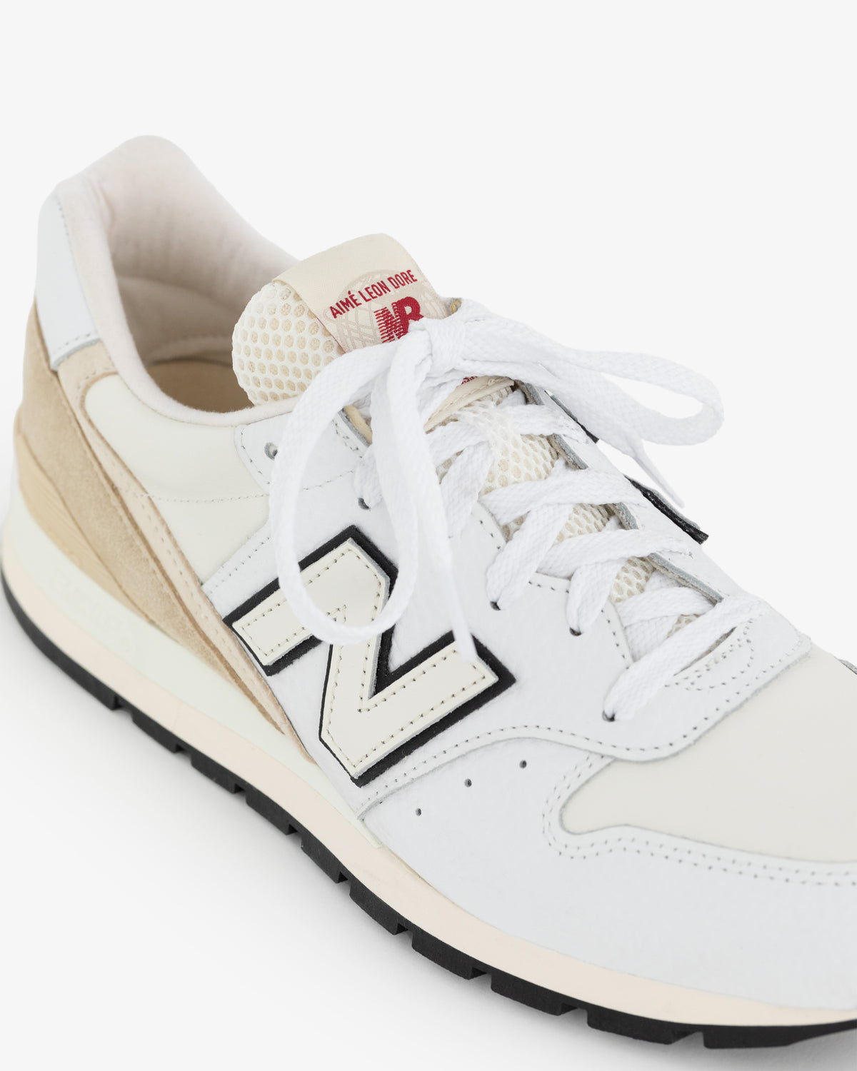 The ALD / NB Made in USA 996 features white and beige colors, white laces, a black N logo, and red tongue branding.