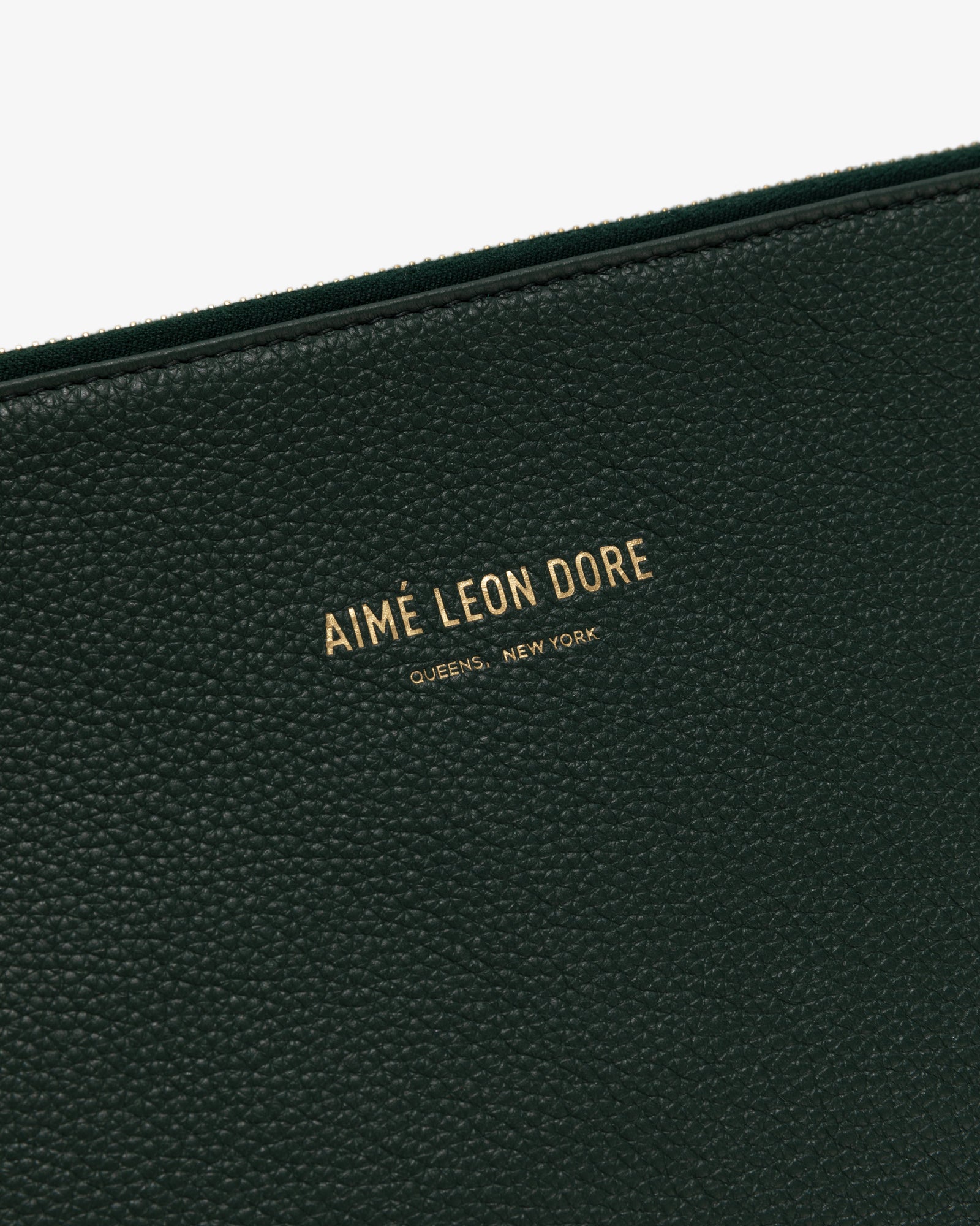 Close-up of Medium Leather Pouch in black textured leather with gold text: AIMÉ LEON DORE QUEENS, NEW YORK.