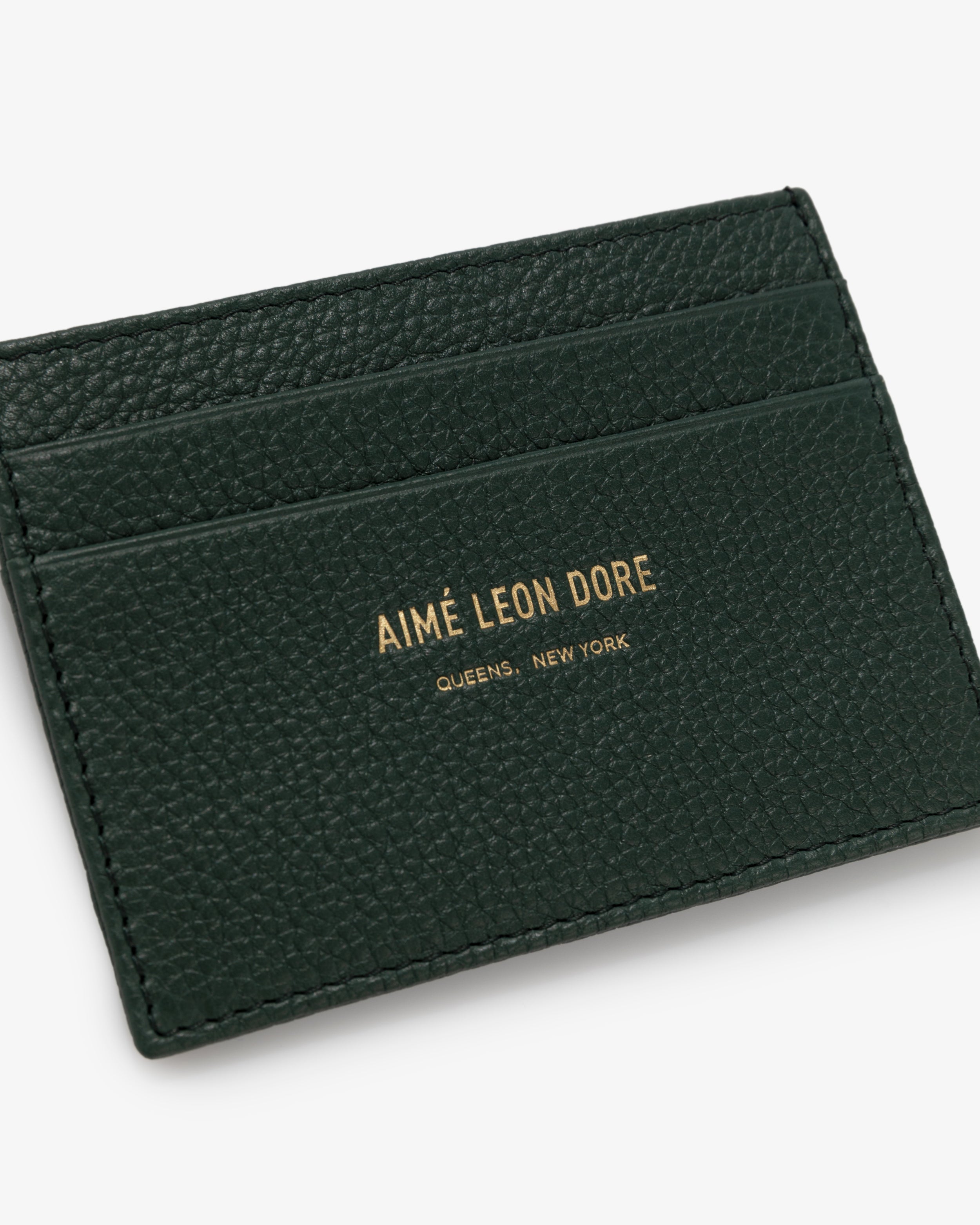 Dark green Leather Card Holder with gold AIMÉ LEON DORE QUEENS, NEW YORK text and three card slots.