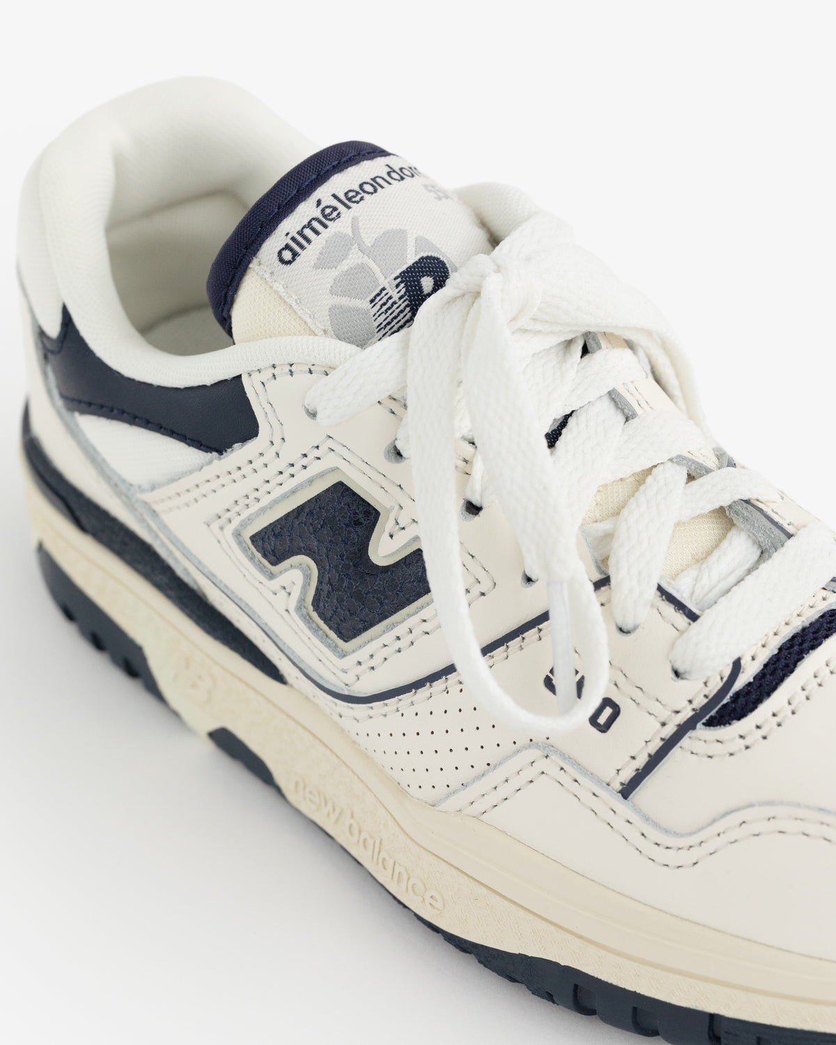 A cream and navy ALD / NB P550 Basketball Oxford for little kids, with branding on the tongue, shown from above.