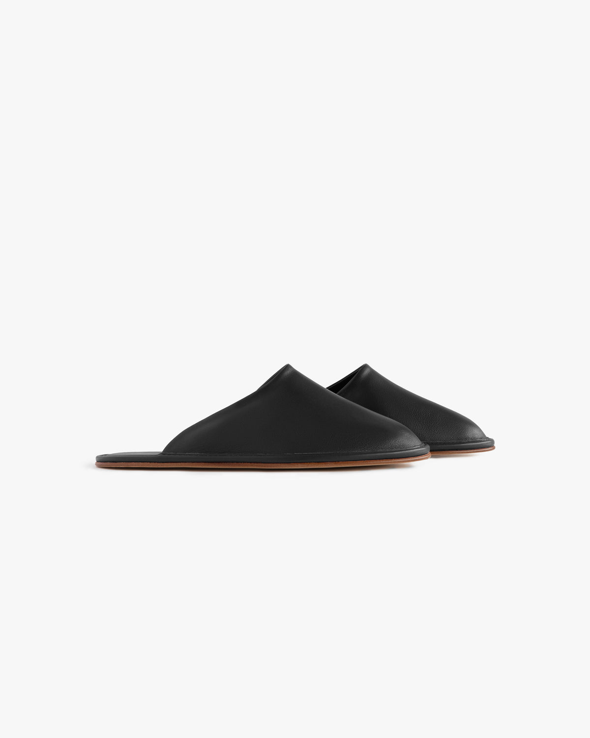 Leather Travel Slipper: black leather slip-ons with flat brown soles, shown on a white background.