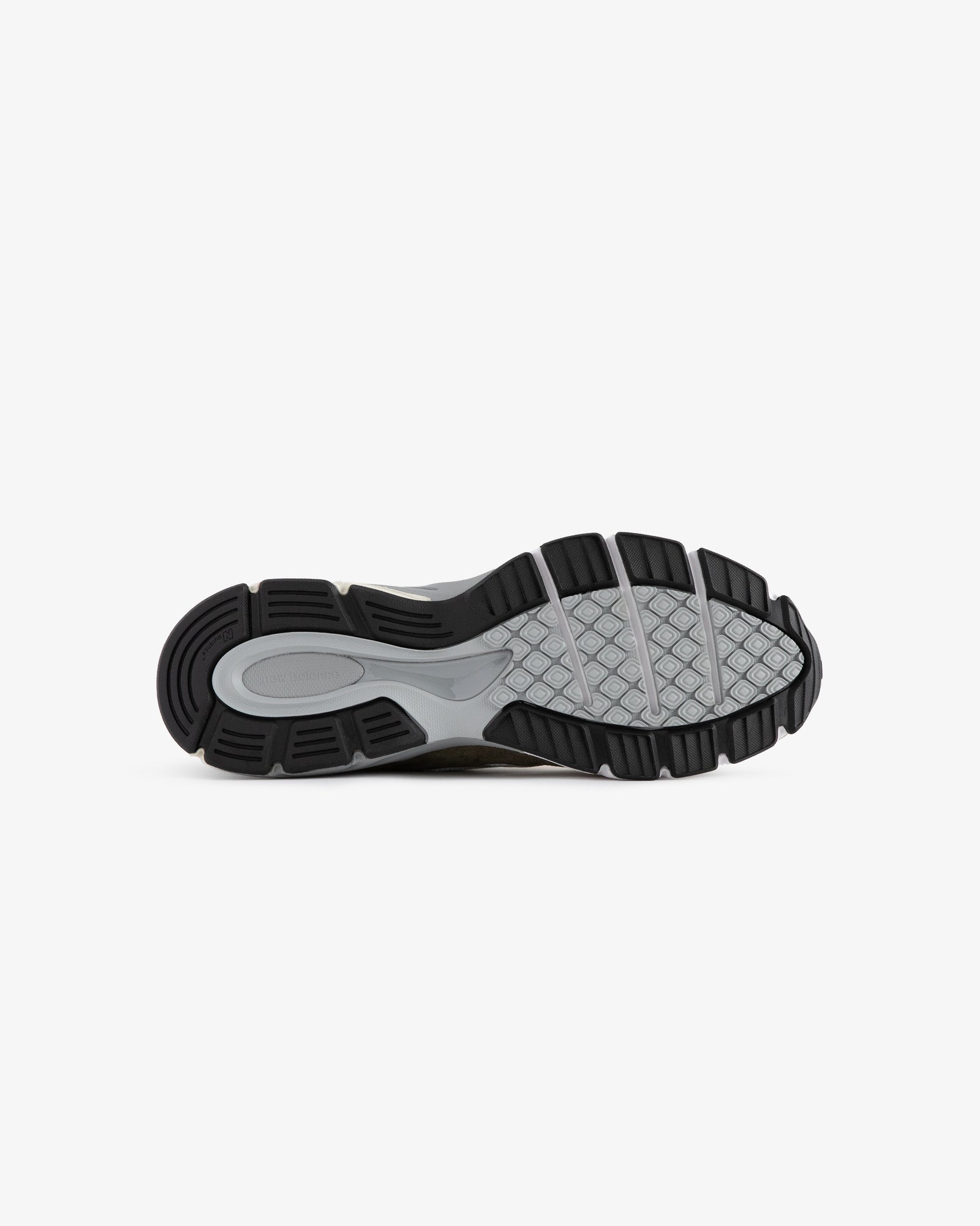 The image shows the black and gray rubber sole of the ALD / New Balance 990v4 sneaker, viewed from the bottom.