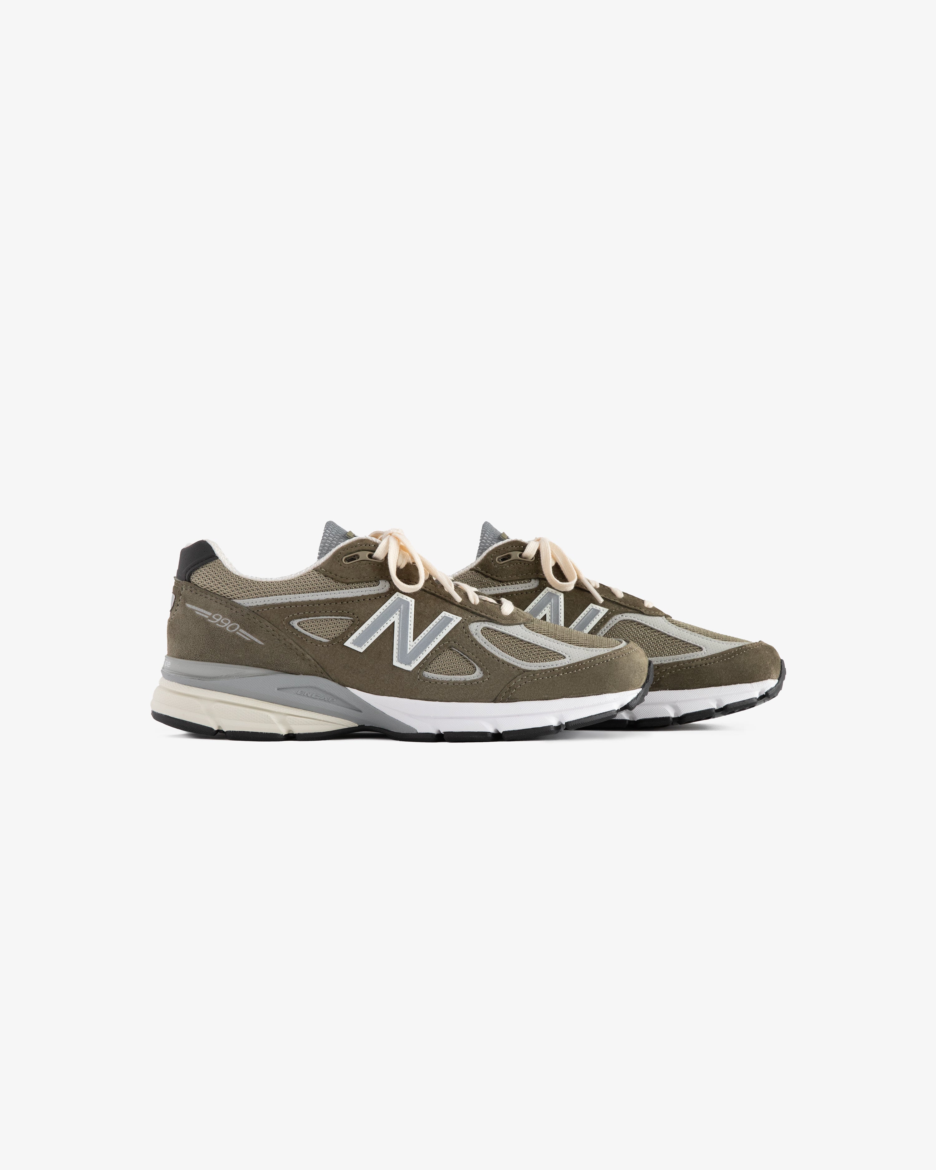 A pair of olive green ALD / New Balance 990v4 sneakers with white soles and beige laces on a white background.