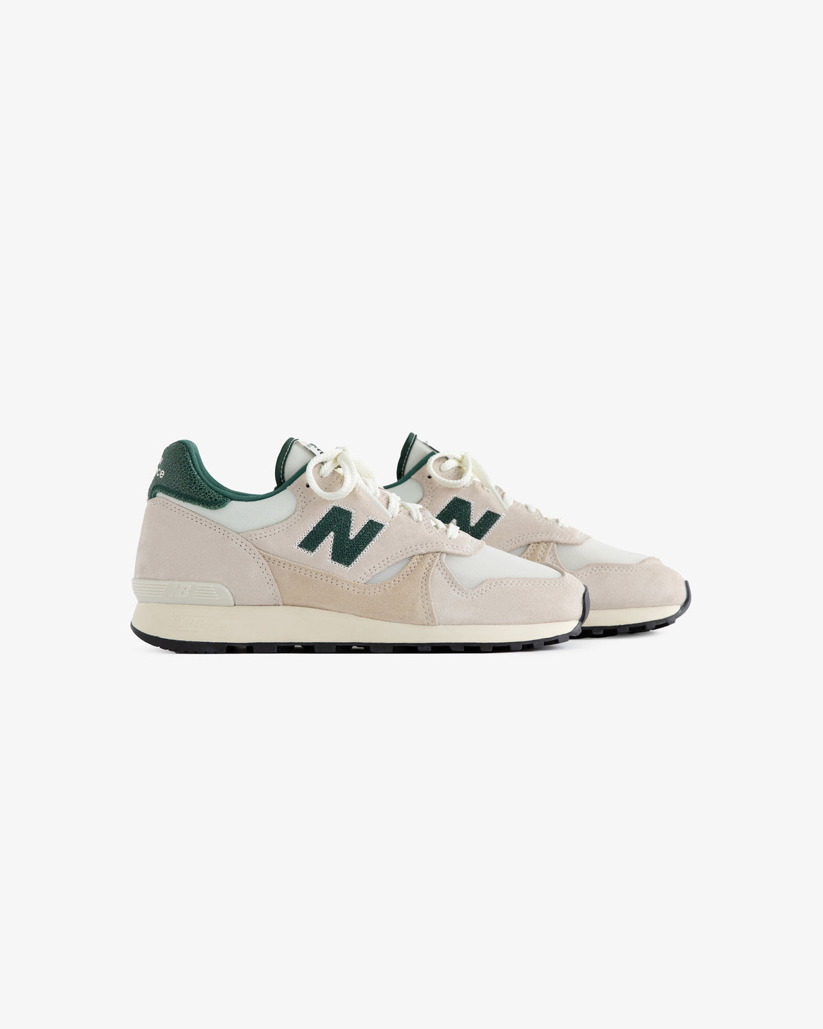 A pair of beige and green ALD / New Balance 475 sneakers with white laces on a white background.