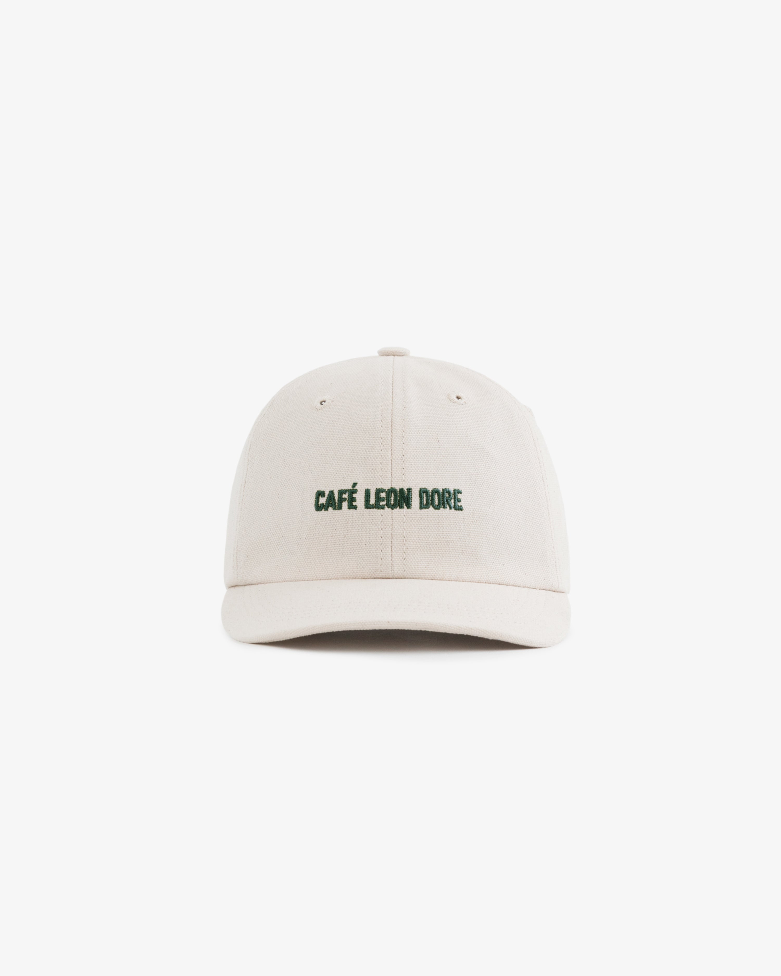 The Café Leon Dore Hat is a beige baseball cap with green embroidered branding on the front, shown on white.