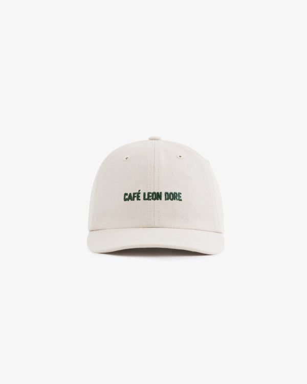 The Café Leon Dore Hat is a beige baseball cap with green embroidered branding on the front, shown on white.