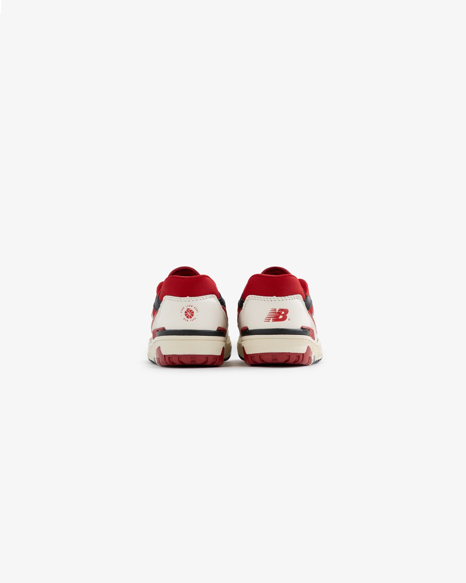 Back view of ALD / NB P550 Basketball Oxfords - Little Kids in white and red with heel logos on a plain white background.