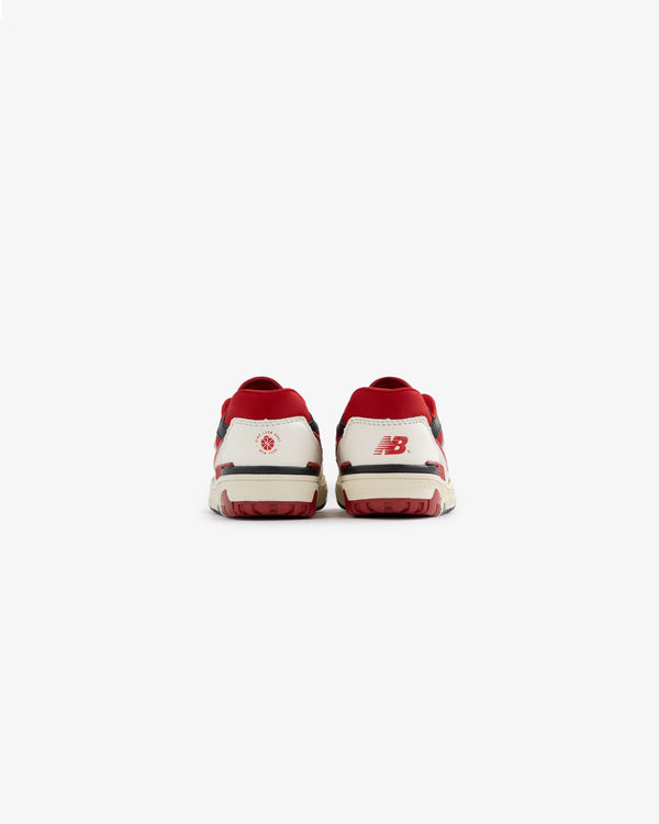 Back view of ALD / NB P550 Basketball Oxfords - Little Kids in white and red with heel logos on a plain white background.