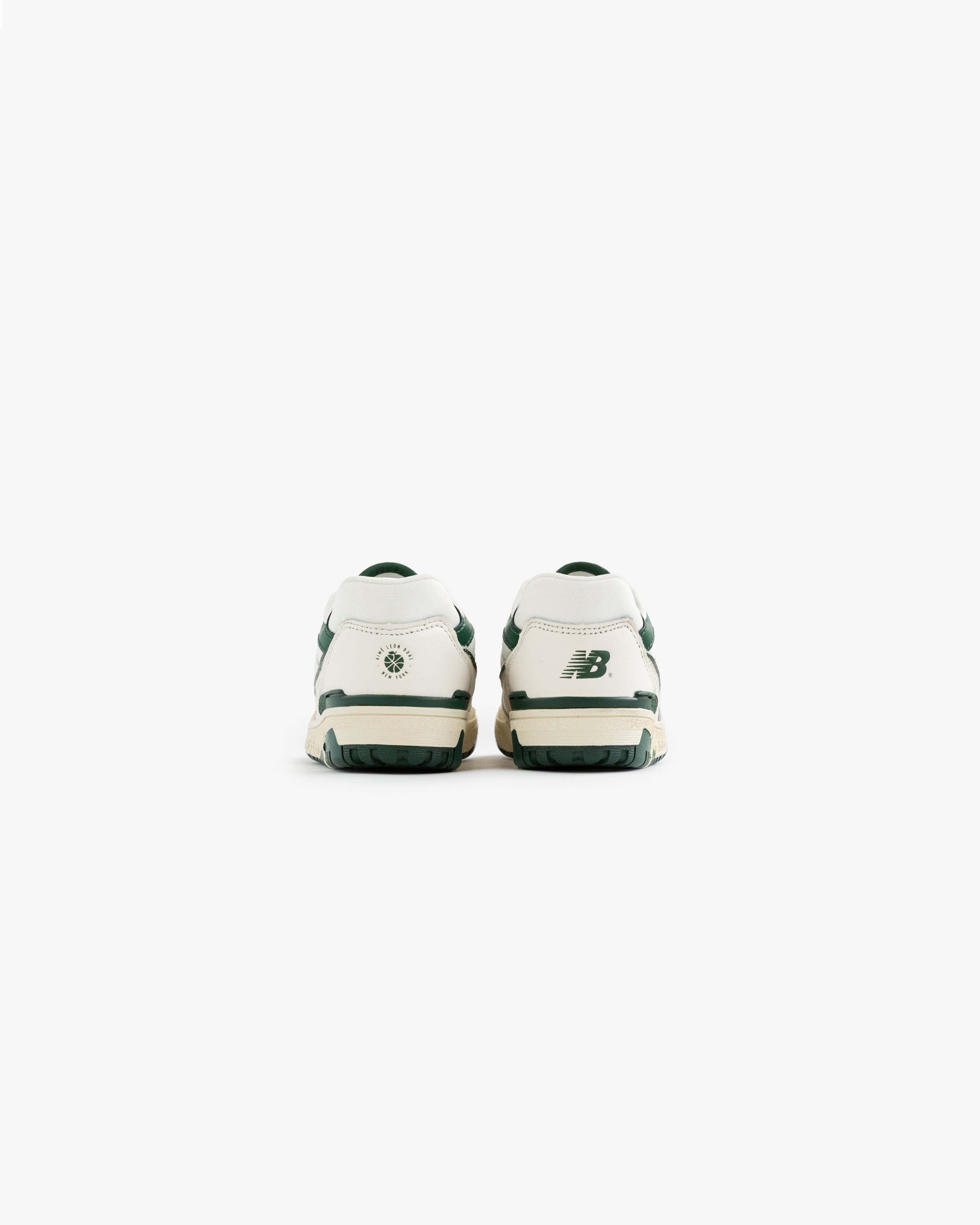 Back view of white and green ALD / NB P550 Basketball Oxfords for little kids on a plain white background.