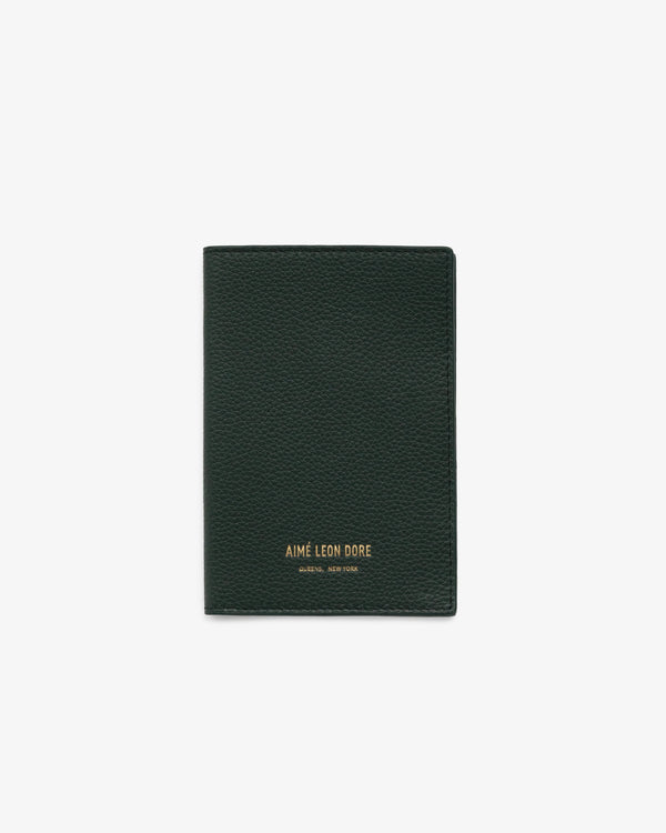Dark green leather passport holder with gold AIMÉ LEON DORE branding at the bottom center, on a white background.