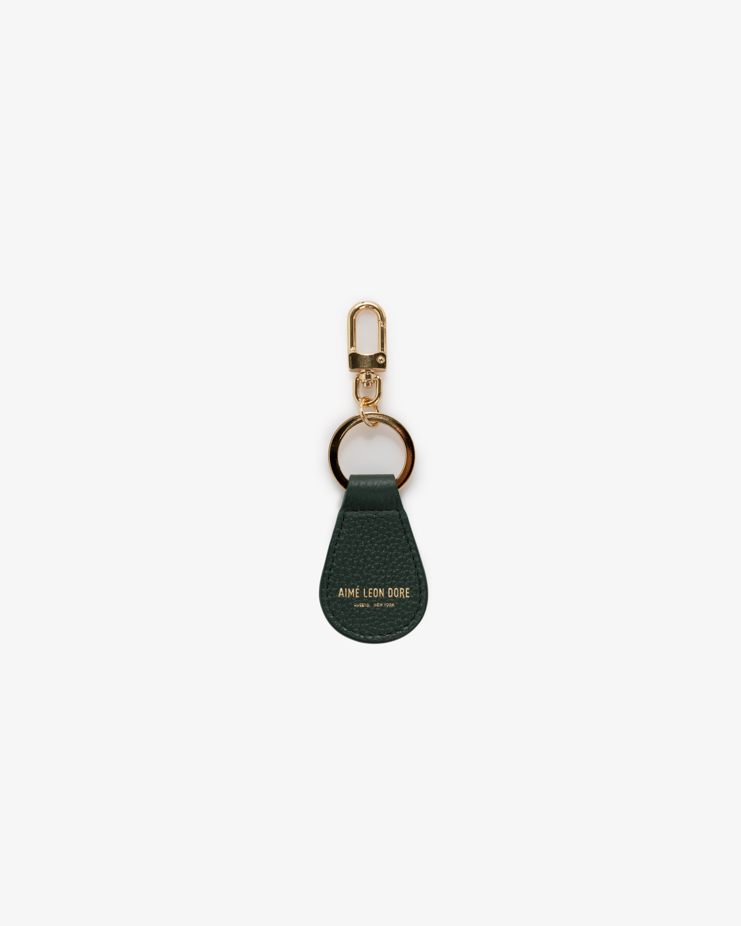 The Leather Key Fob is dark green leather with gold hardware and "Aime Leon Dore" embossed in gold at the bottom.