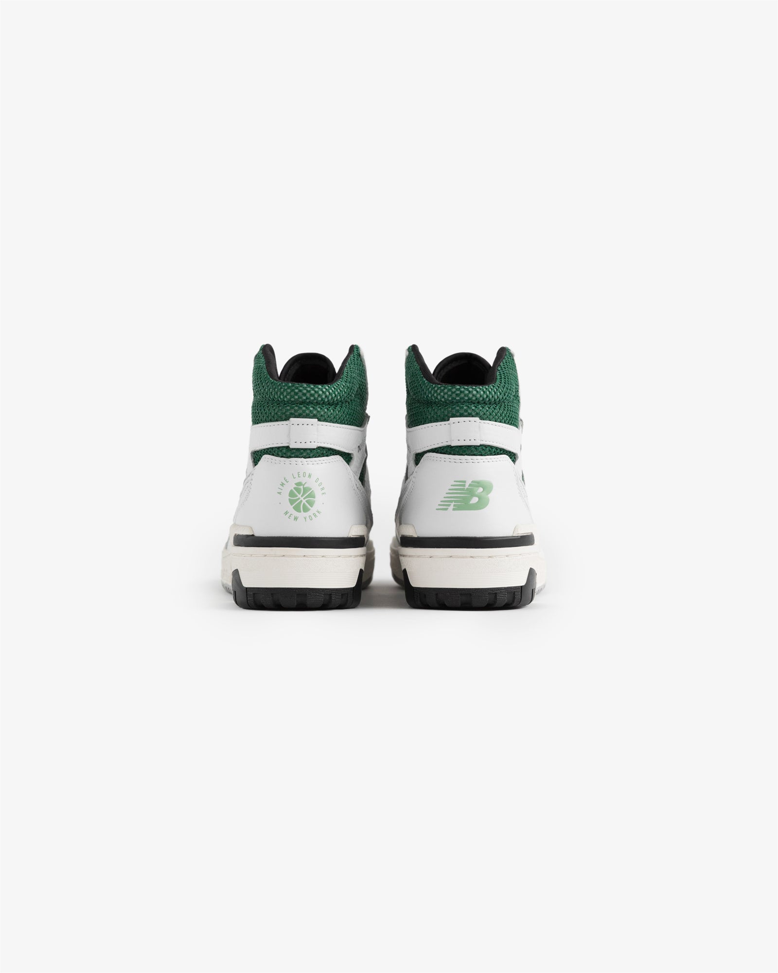 A pair of ALD / New Balance 650R sneakers in white and green shown from the back on a plain white background.