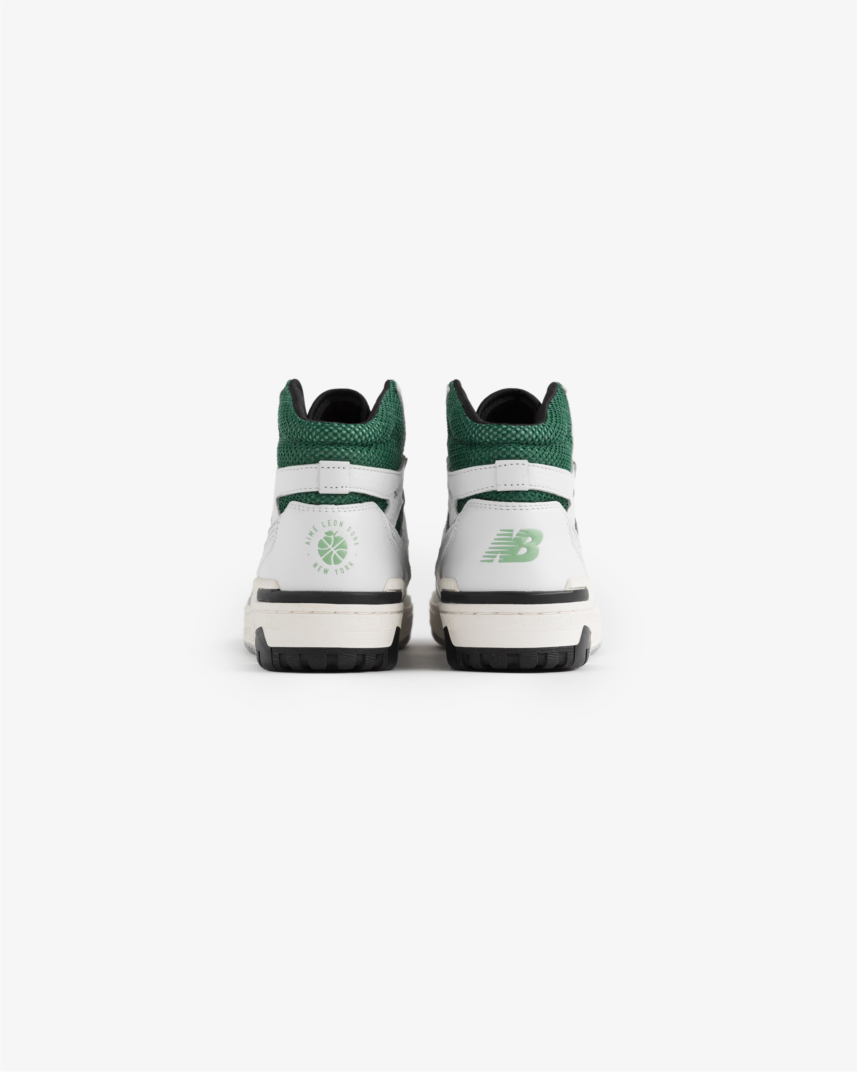 A pair of ALD / New Balance 650R sneakers in white and green shown from the back on a plain white background.