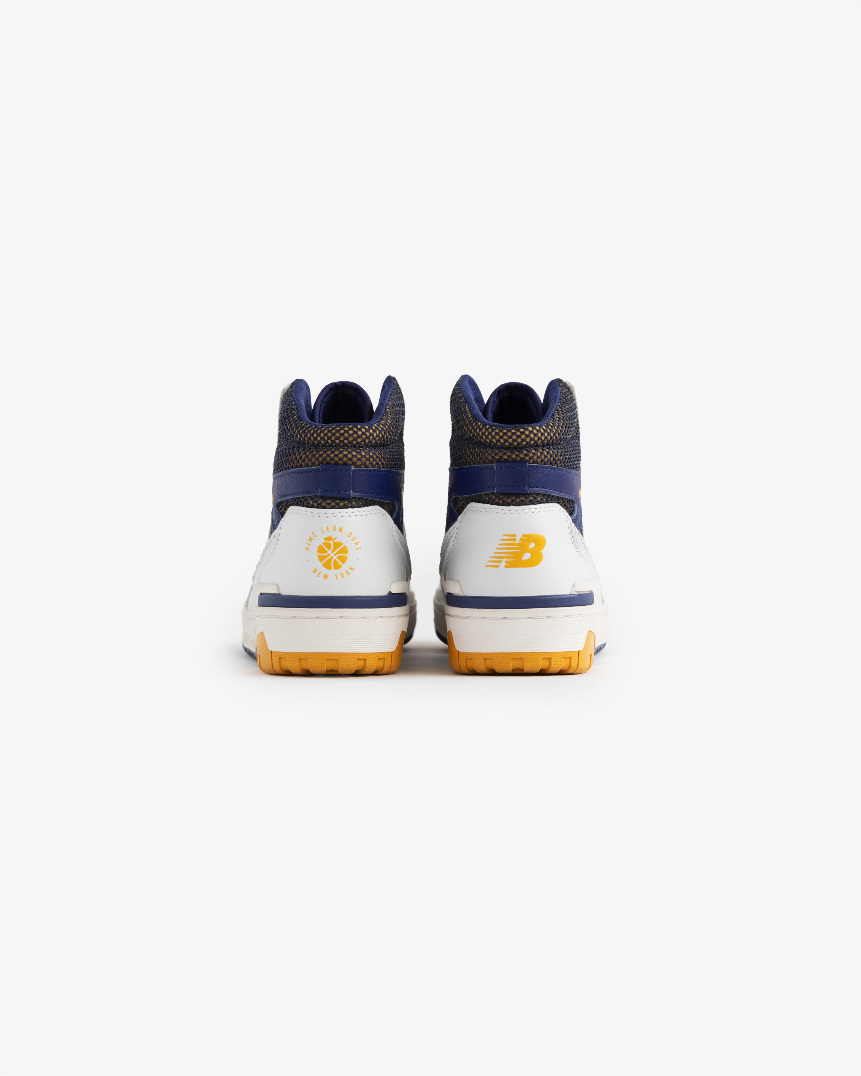 Back view of ALD / New Balance 650R sneakers in white, blue, and yellow with heel logos on a white background.