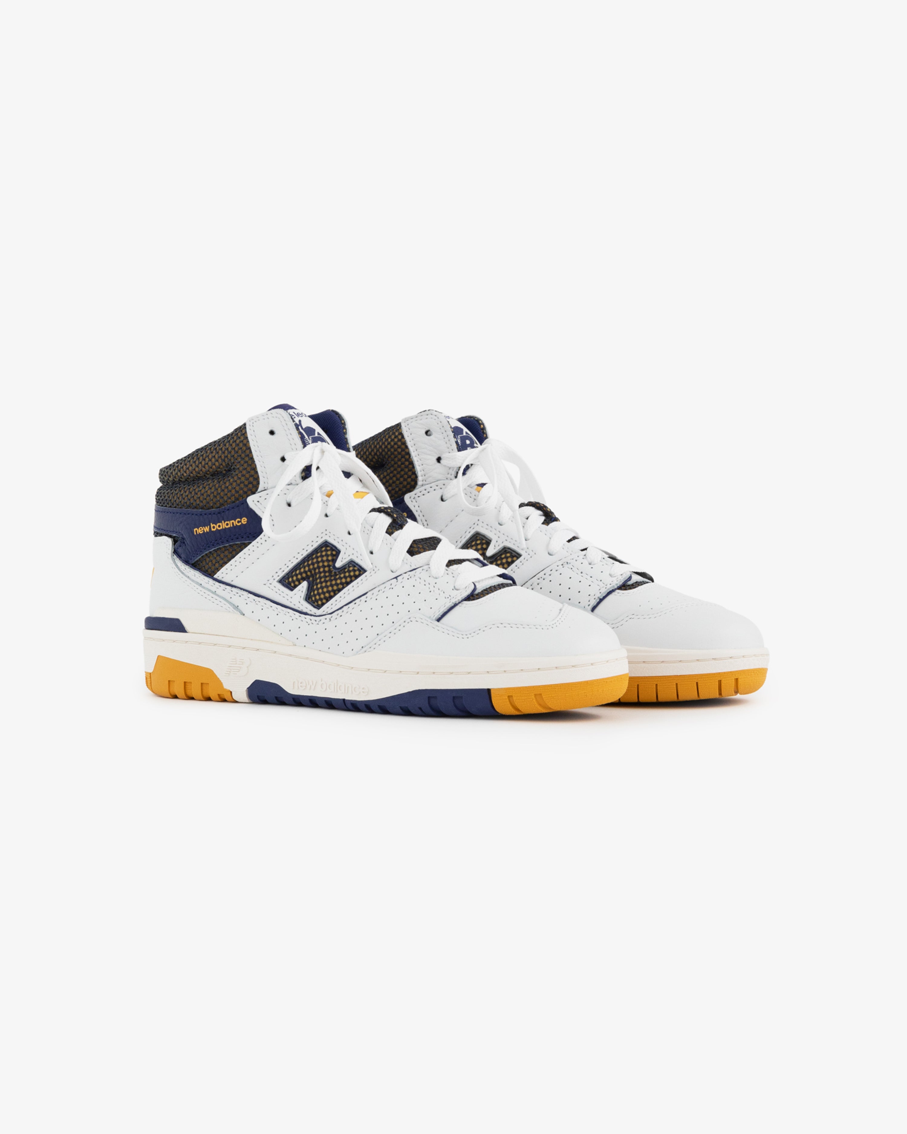 The ALD / New Balance 650R is a high-top sneaker in white, navy, and yellow with a perforated toe and mesh accents.