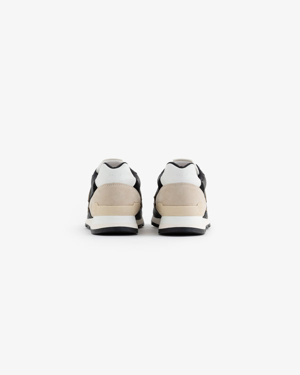 A pair of ALD / NB Made in USA 996 sneakers in black, white, and beige shown from the back on a white background.