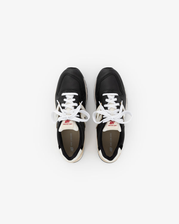 The ALD / NB Made in USA 996 sneakers are black with white laces, shown from above on a white background.