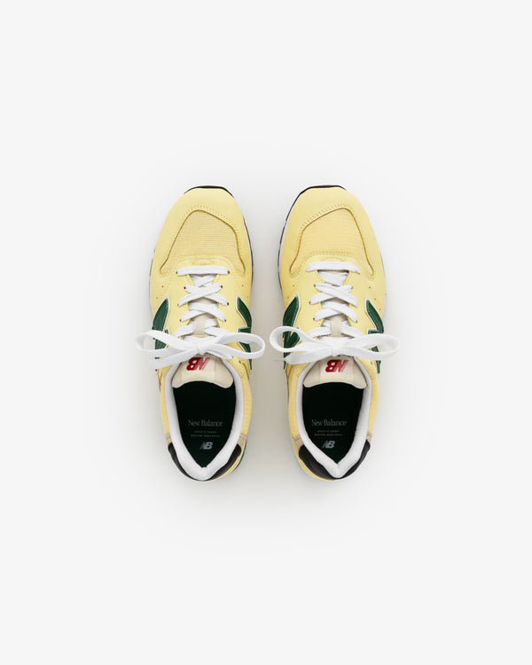 A pair of yellow and green New Balance Made in USA 996 sneakers viewed from above on a white background.