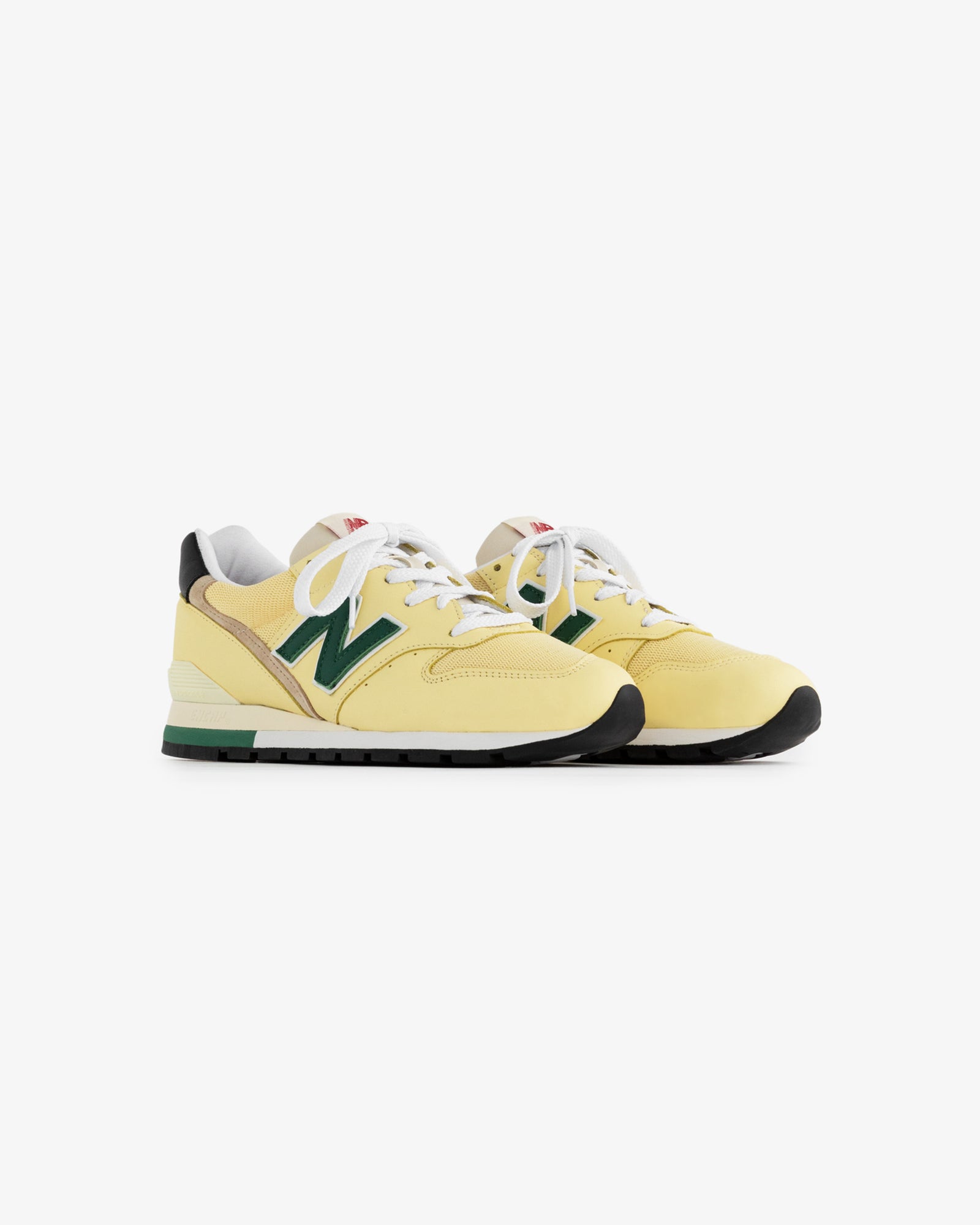 A pair of yellow New Balance Made in USA 996 sneakers with green accents, white laces, and black soles.