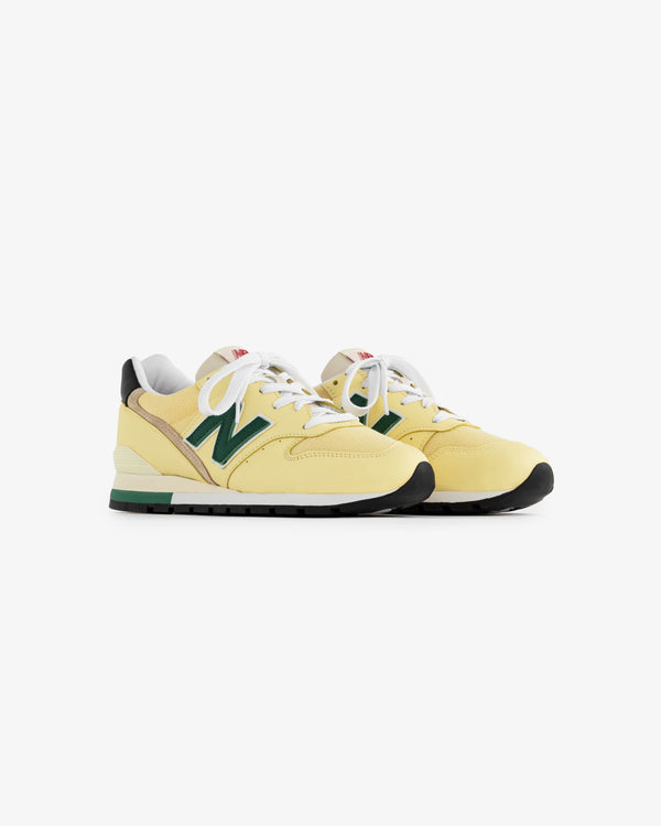 A pair of yellow New Balance Made in USA 996 sneakers with green accents, white laces, and black soles.