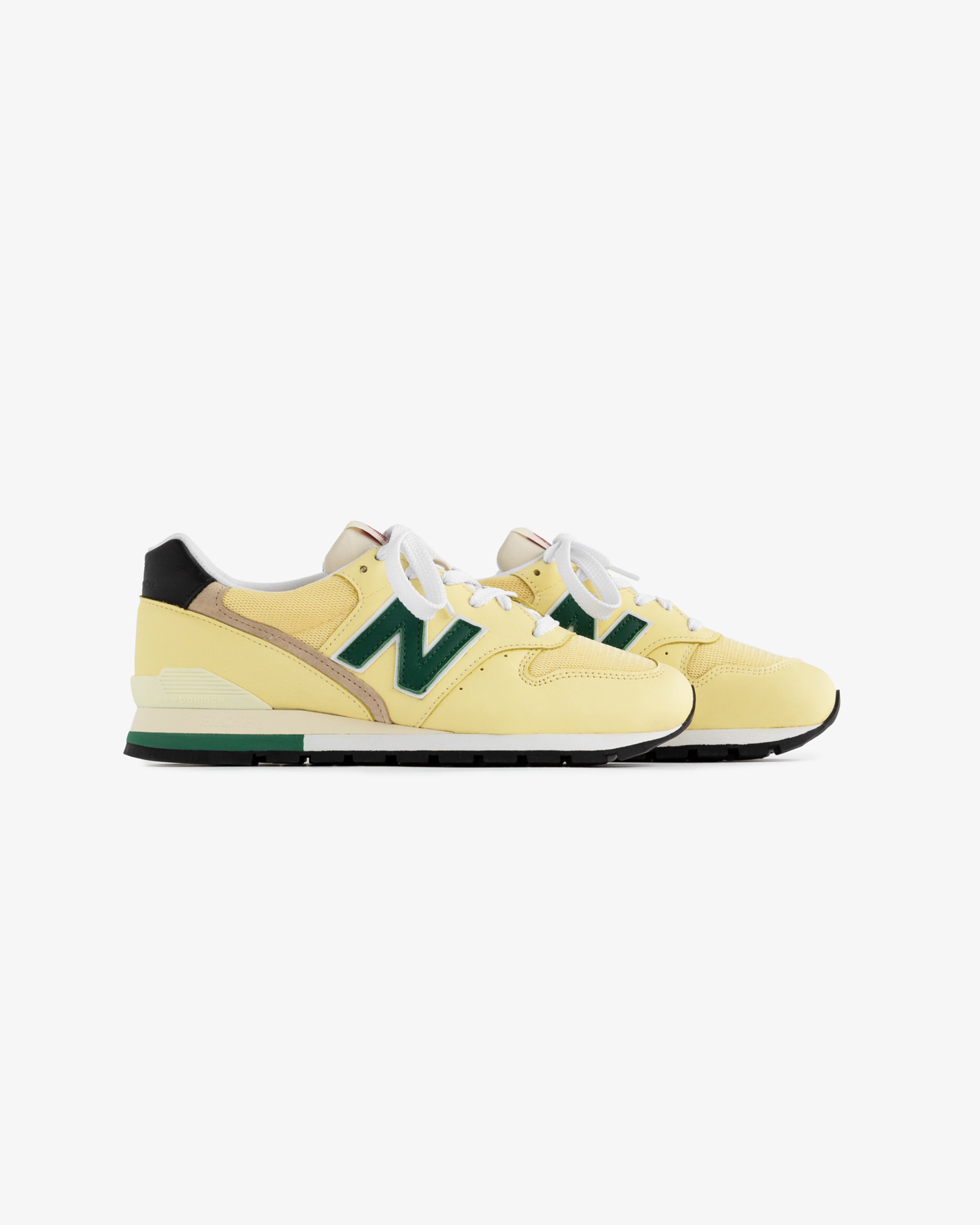 Yellow New Balance Made in USA 996 sneakers with green accents and white laces on a white background.