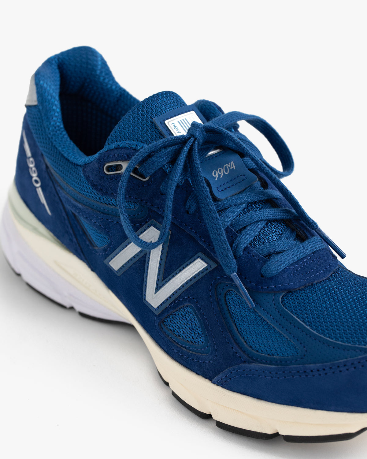 ALD / NB Made in USA 990v4 sneaker in blue with silver accents and white sole, shown on a white background.