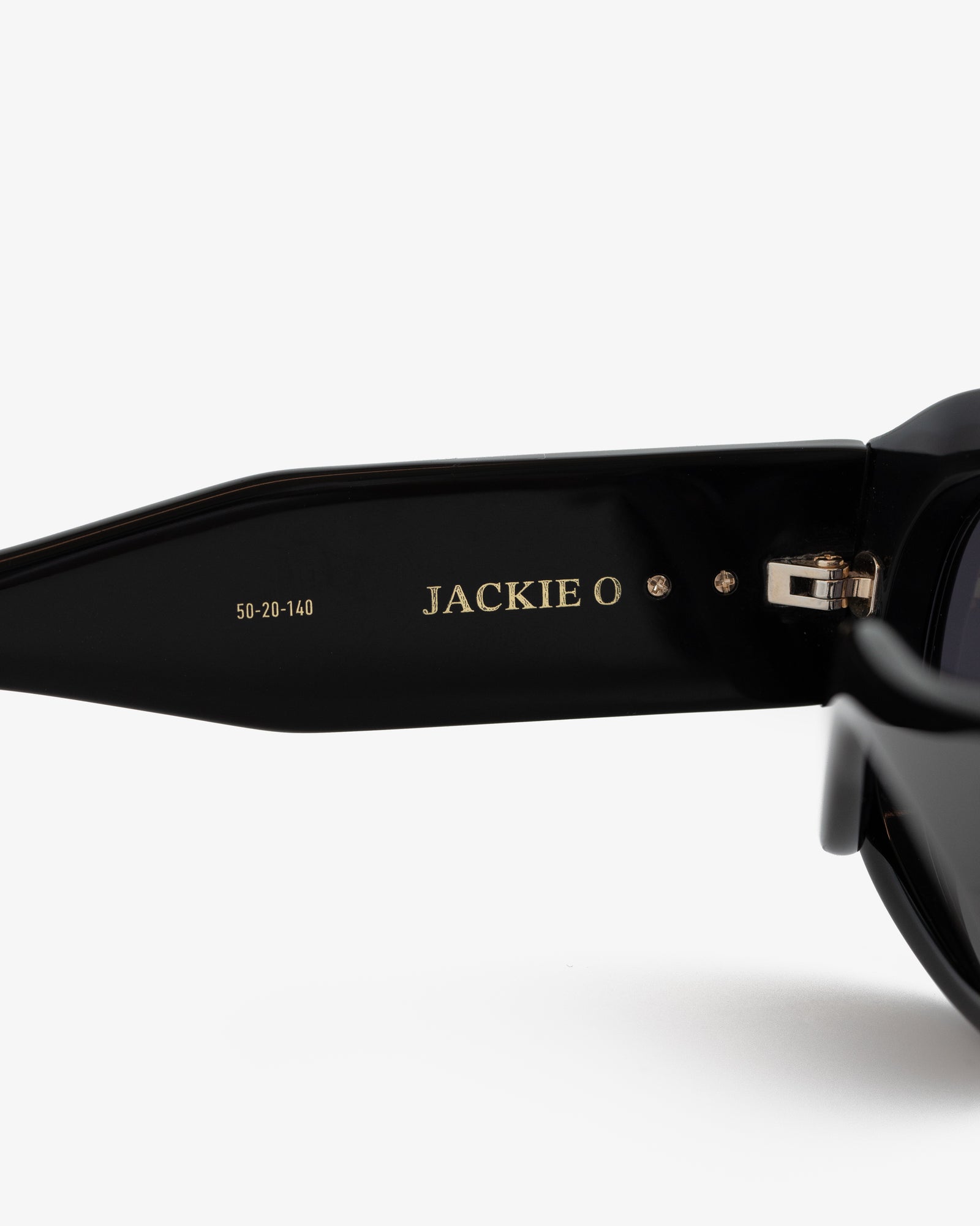 Close-up of Jackie O Sunglasses' black arm with gold branding and size numbers printed inside.