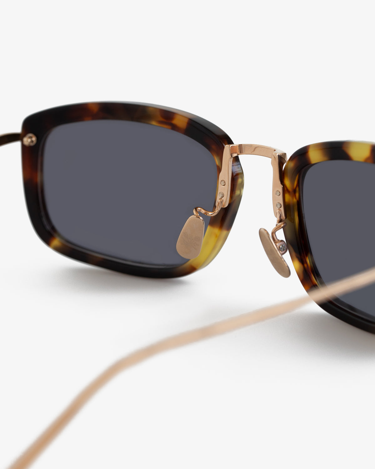 Close-up of Ace Sunglasses featuring tortoiseshell frames, dark lenses, and gold nose pads on a white background.