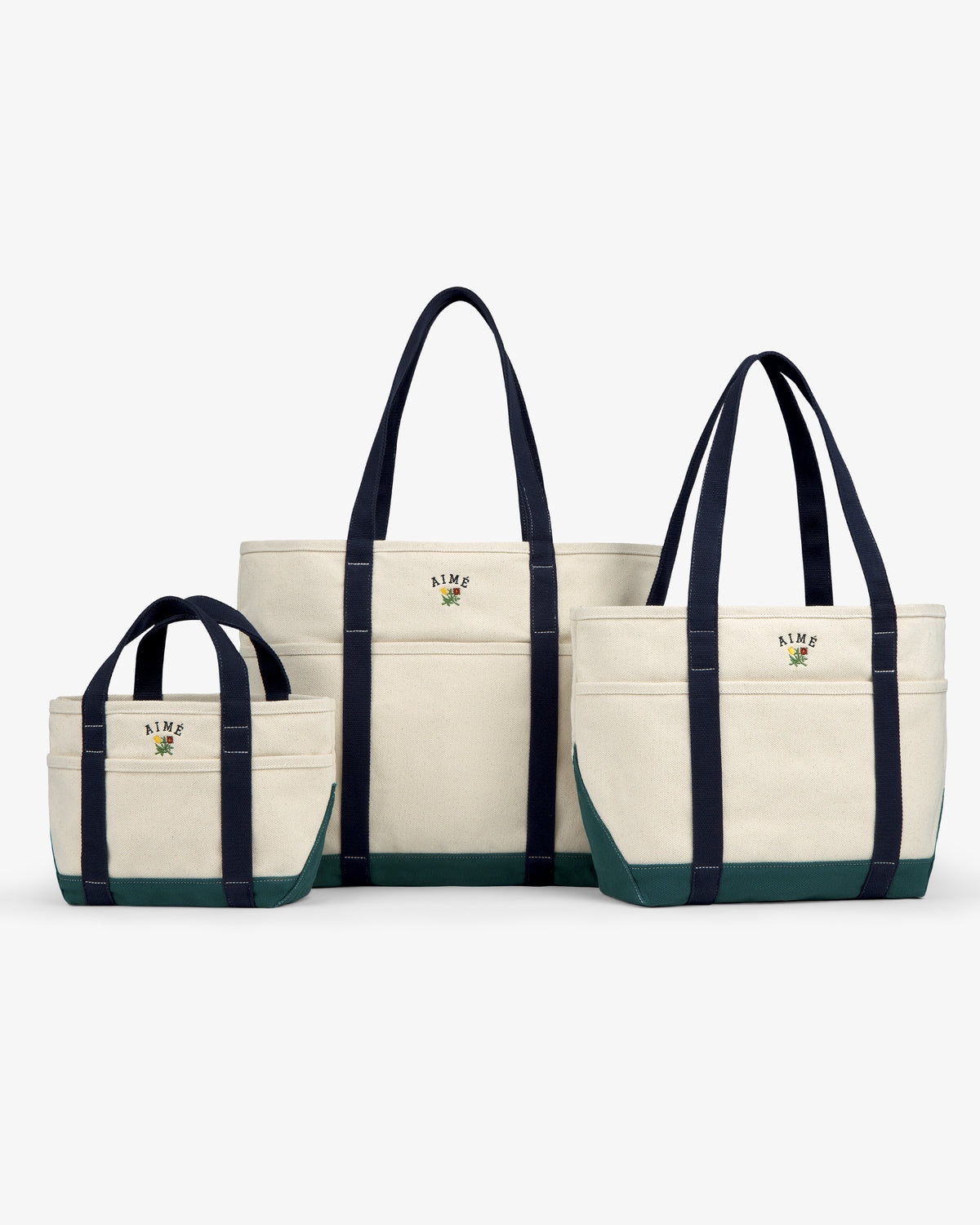 Three Mini Crest Contrast Tote Bags in various sizes, navy handles, green bottoms, displayed on a white background.