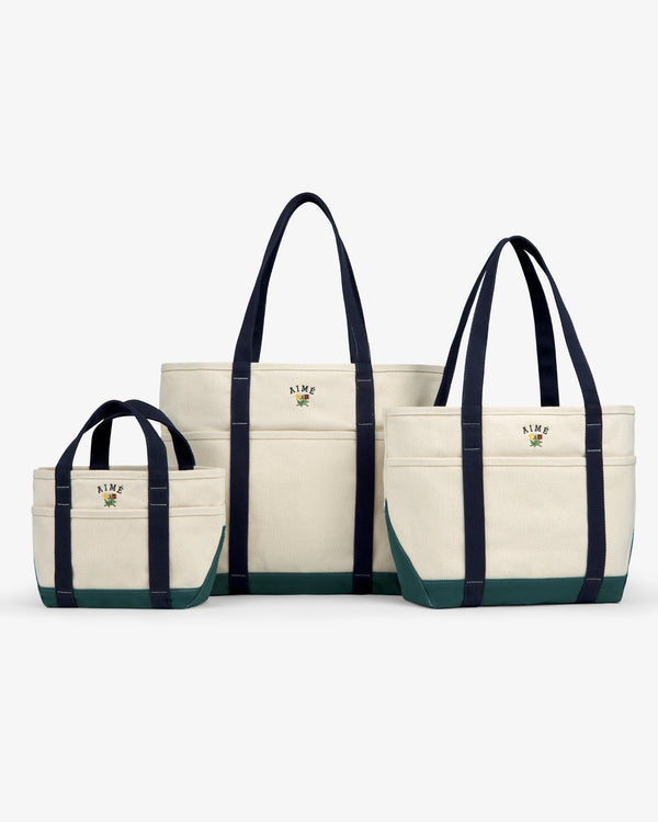 Three Mini Crest Contrast Tote Bags in various sizes, navy handles, green bottoms, displayed on a white background.