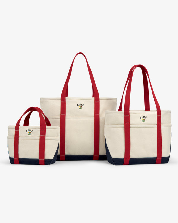 Three Mini Crest Contrast Tote Bags with red handles, navy bottoms, and logos in small, medium, and large sizes.