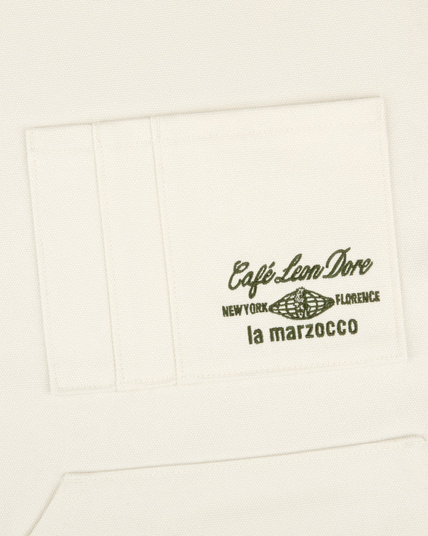 White apron pocket with green text "Café Leon Dore / La Marzocco" and a coffee bean illustration.