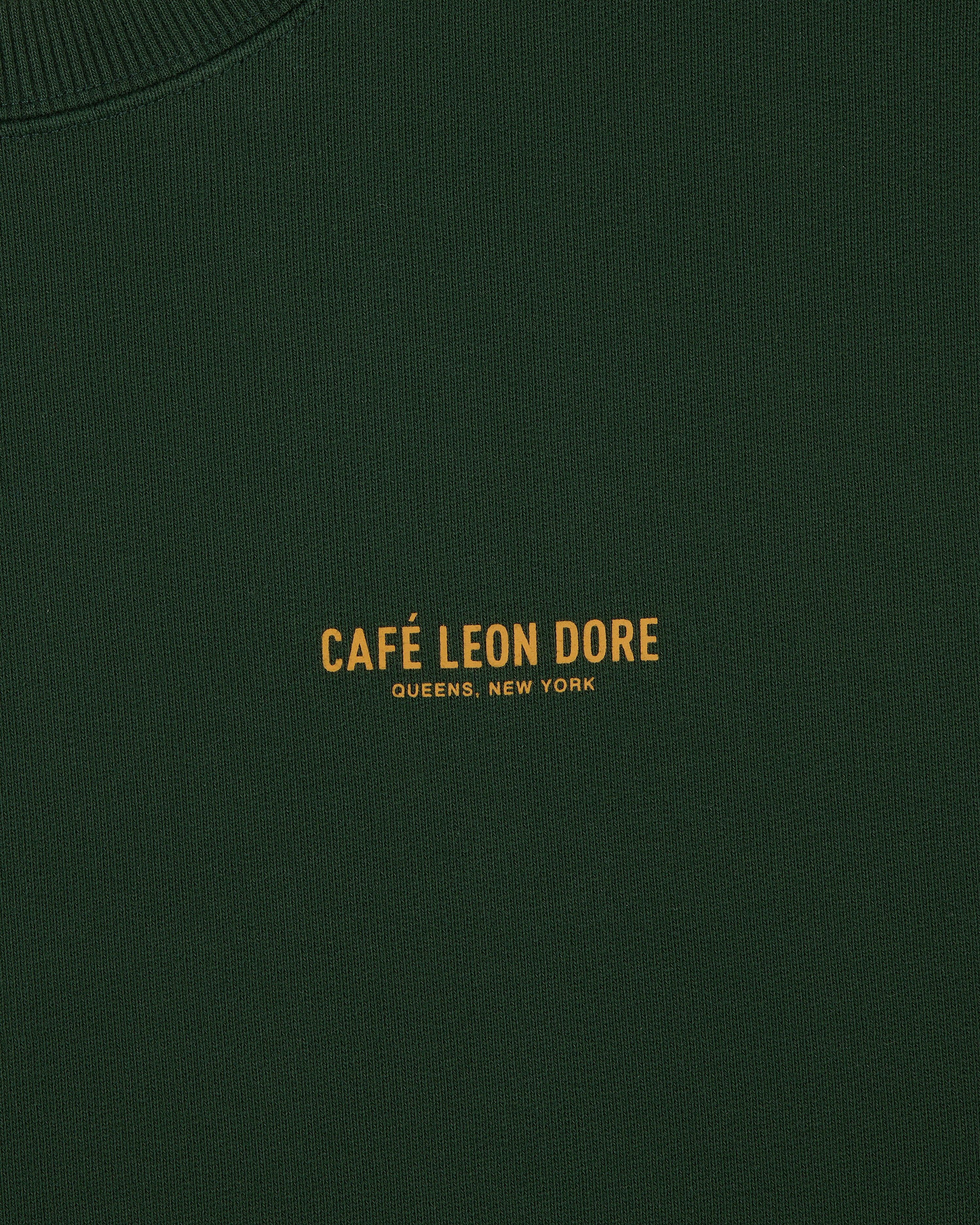 Dark green Café Leon Dore Crewneck Sweatshirt with yellow "CAFÉ LEON DORE QUEENS, NEW YORK" text at center.