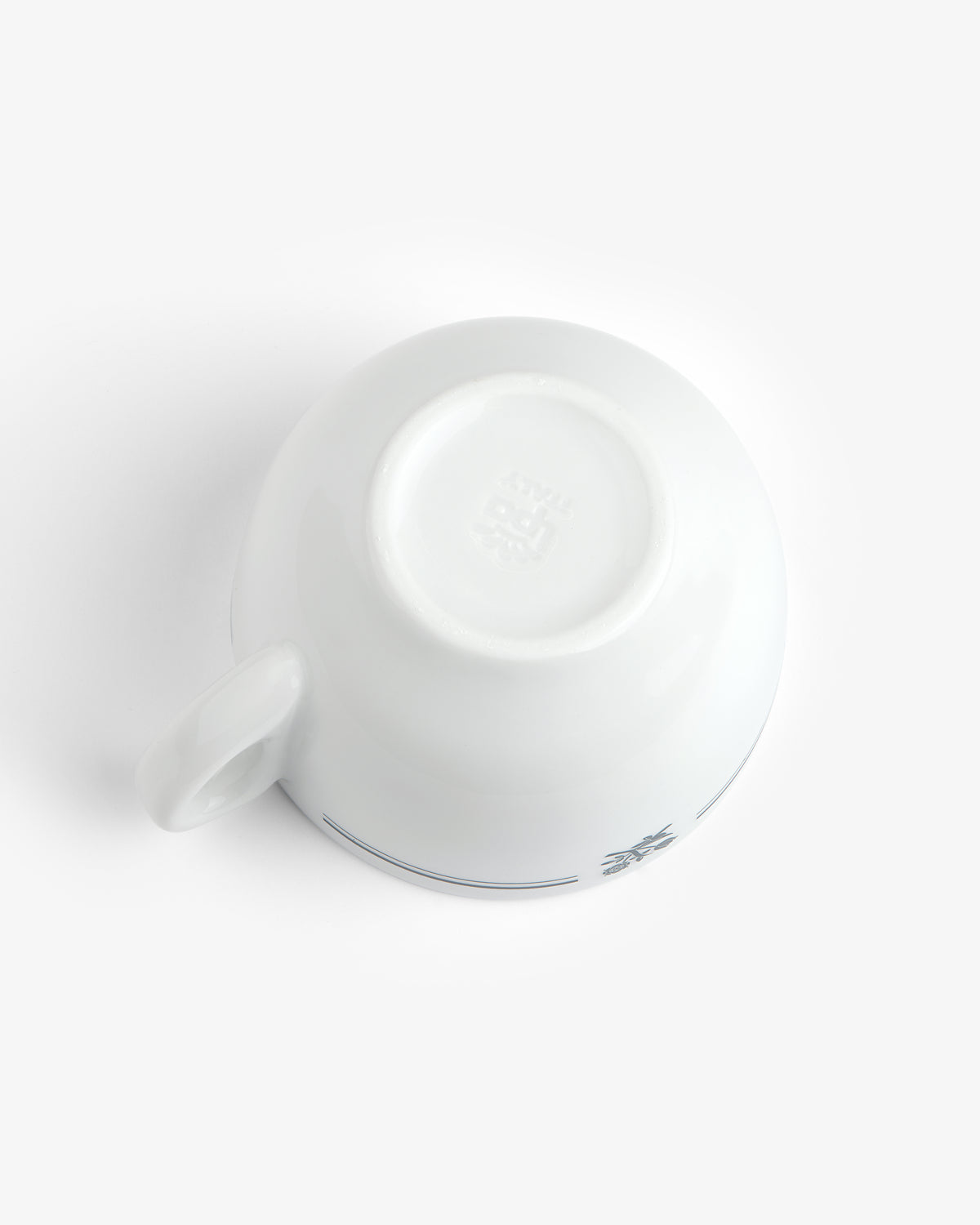 Café Leon Dore Cappuccino Cup & Saucer set, white ceramic cup upside down, handle shown left, plain background.