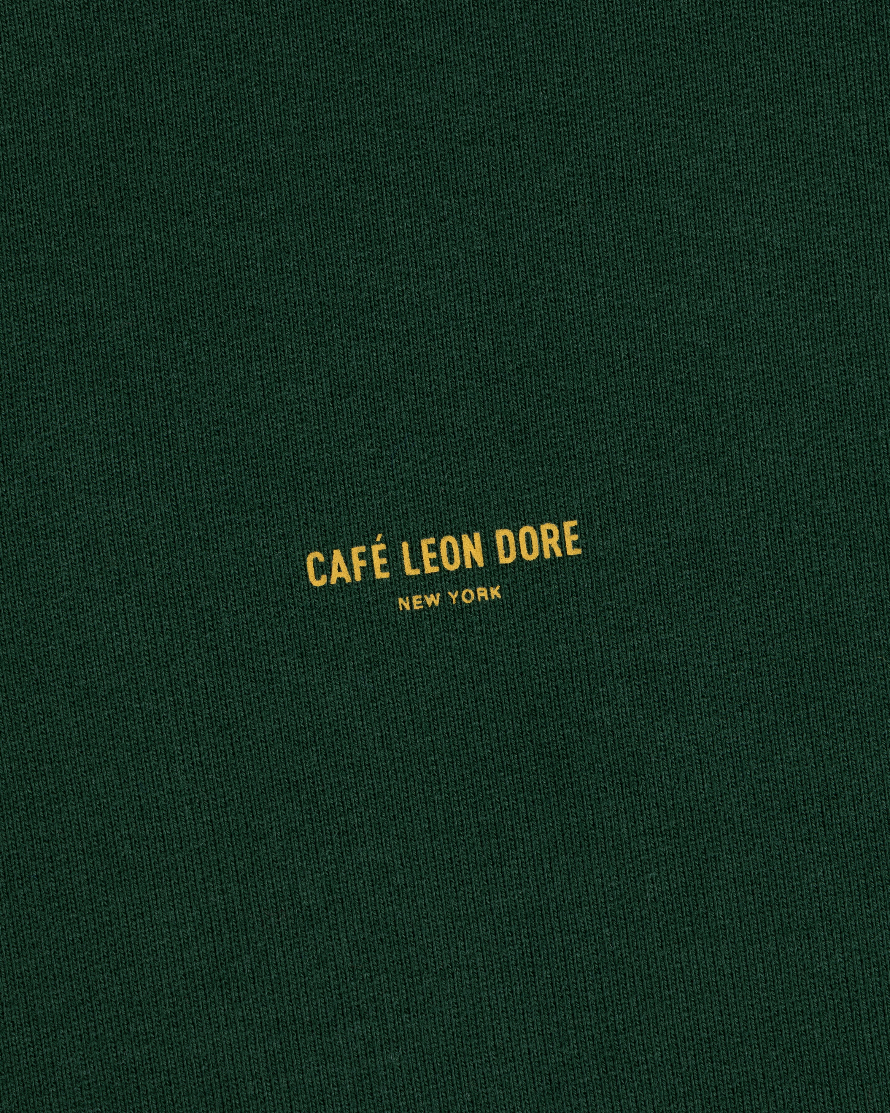 Dark green Café Leon Dore Crewneck Sweatshirt with small yellow “CAFÉ LEON DORE NEW YORK” centered on the front.