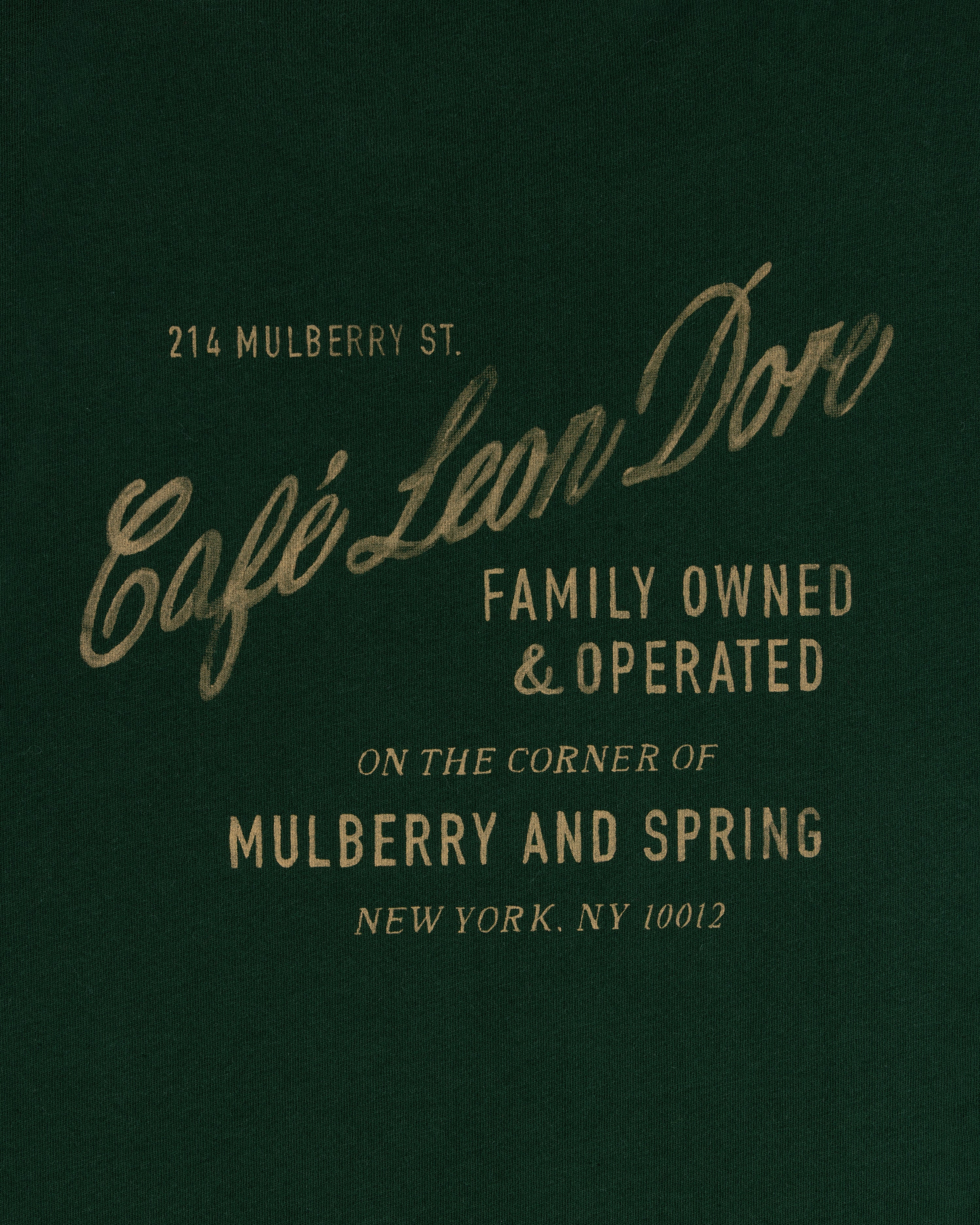 Green tee with gold text: Café Leon Dore, Family Owned & Operated, Mulberry and Spring, NYC.