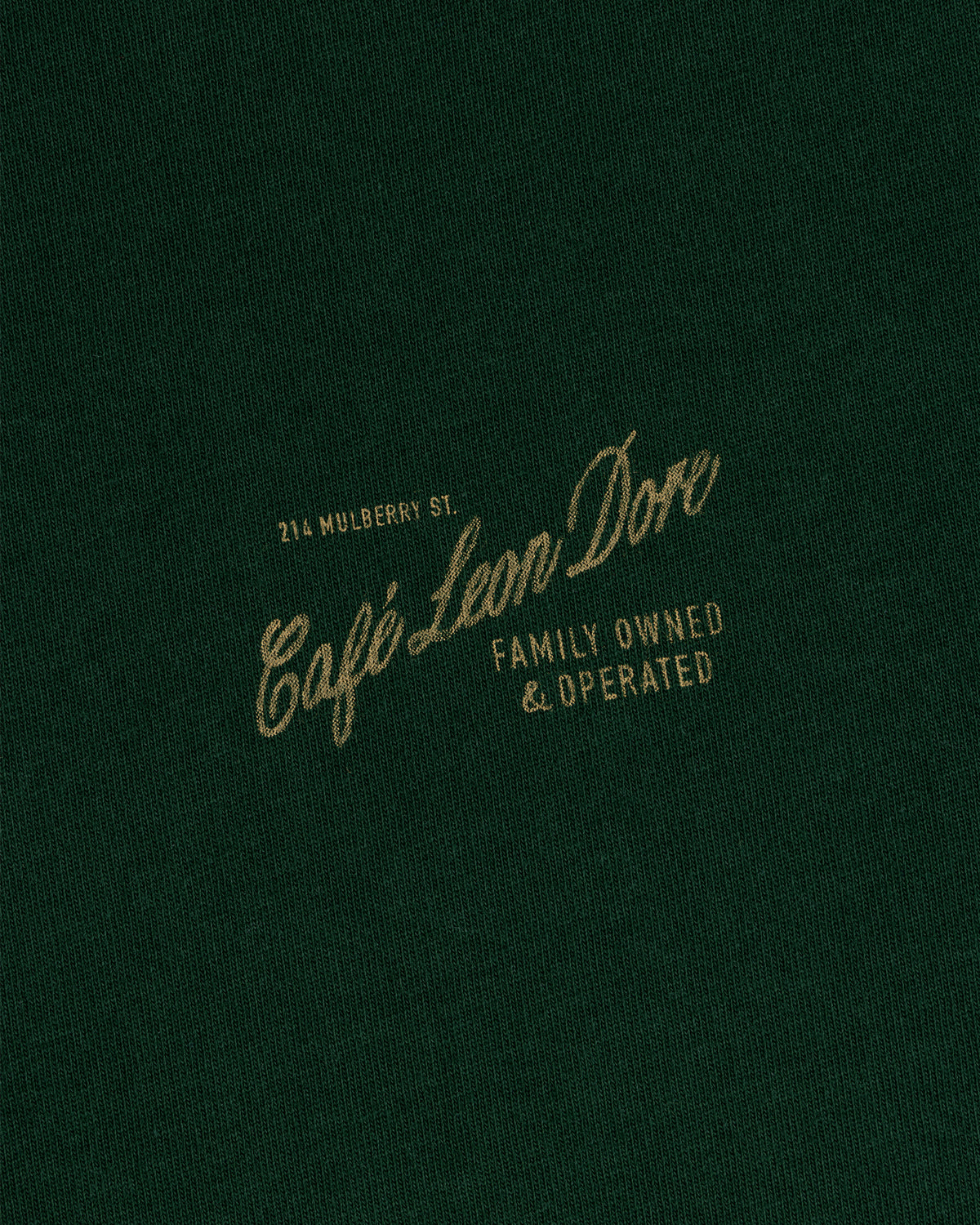 Dark green Café Leon Dore Mulberry Tee with gold text: 214 Mulberry St., Family Owned & Operated.