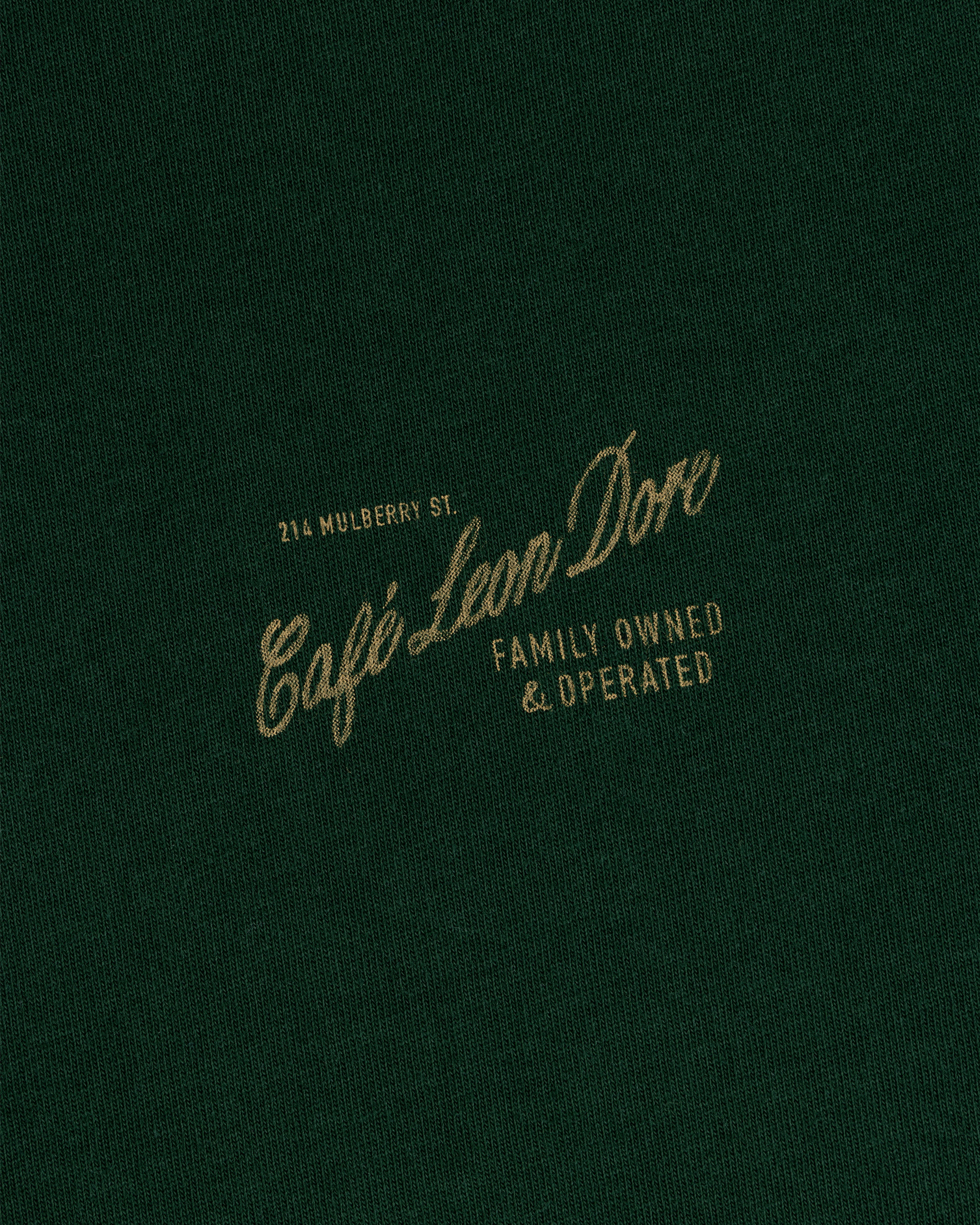Dark green Café Leon Dore Mulberry Tee with gold text: 214 Mulberry St., Family Owned & Operated.