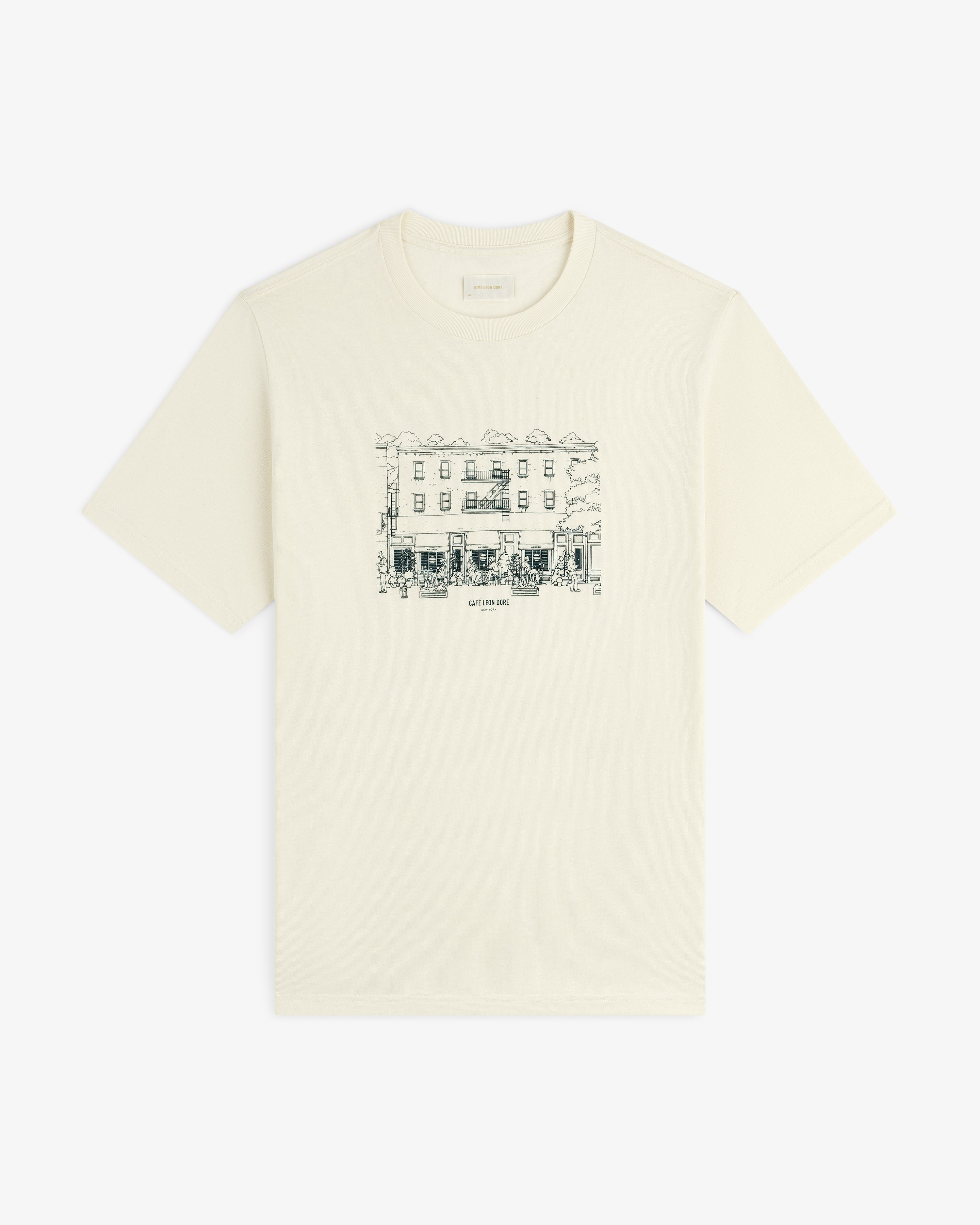 Café Leon Dore Storefront Tee: Off-white tee with black line art of a building and trees on the chest.