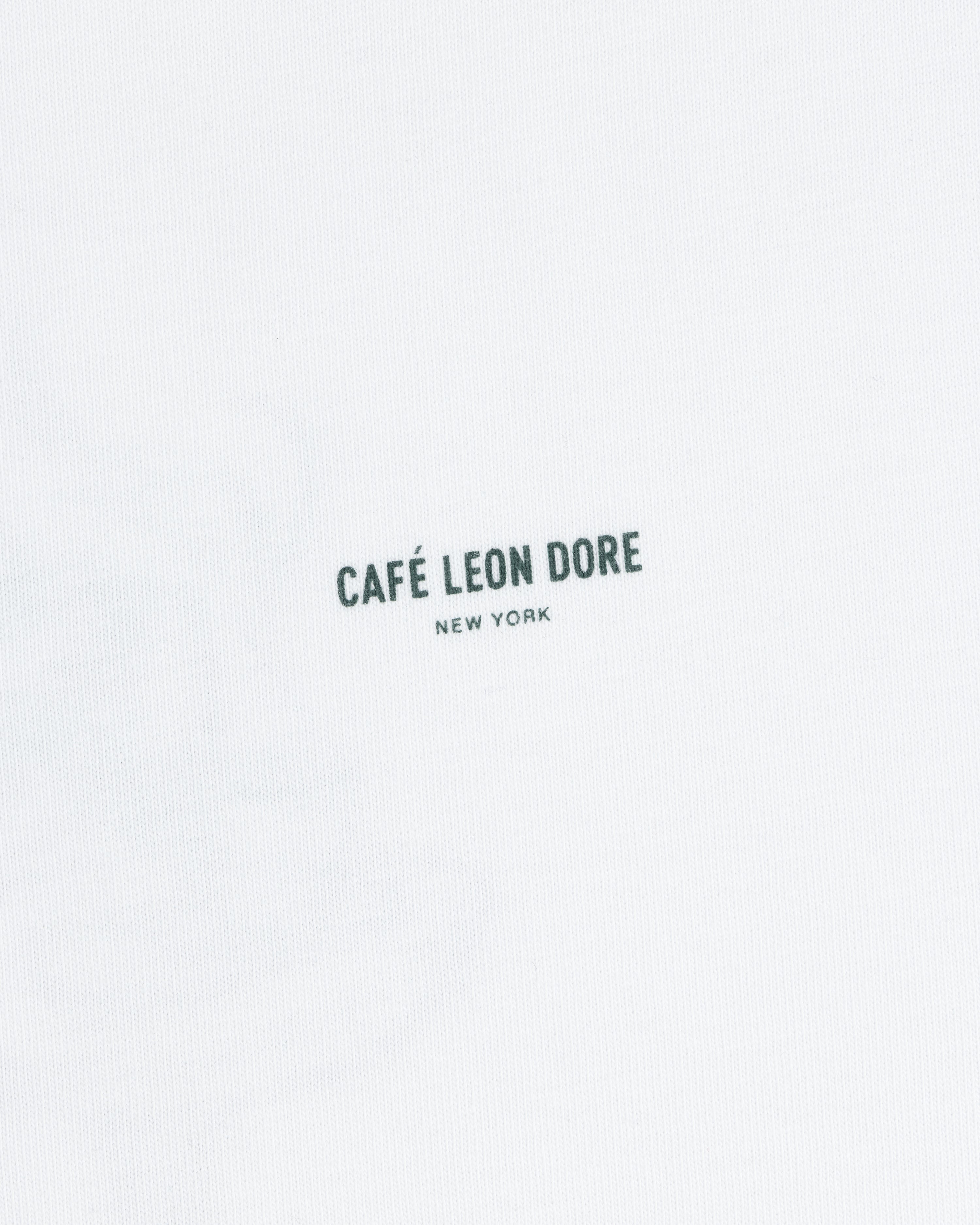 White Café Leon Dore Caricature Tee featuring small, dark “CAFÉ LEON DORE NEW YORK” print at the center.